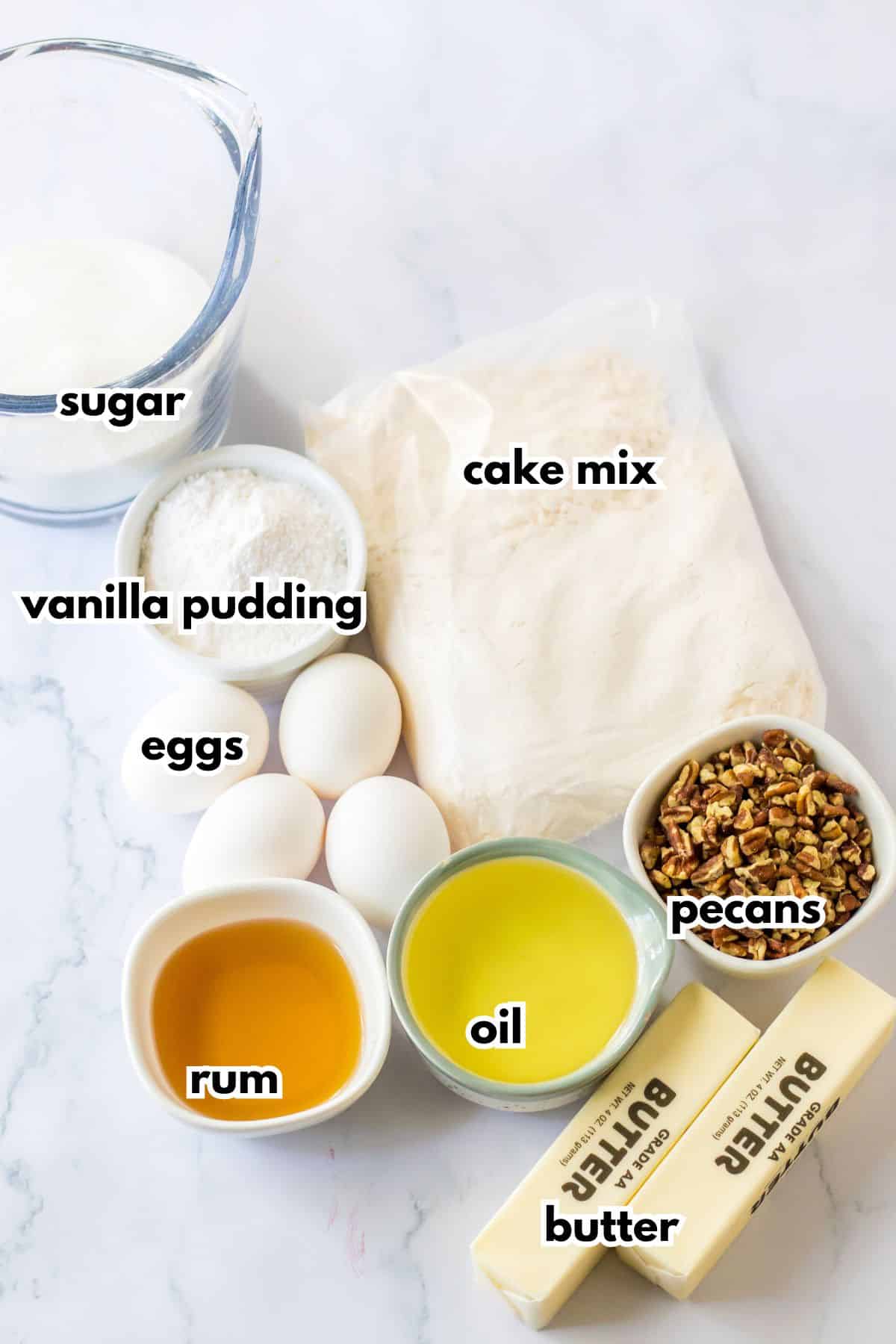 bowls of sugar, vanilla pudding, rum, oil, pecans, eggs, bag of cake mix, and sticks of butter.