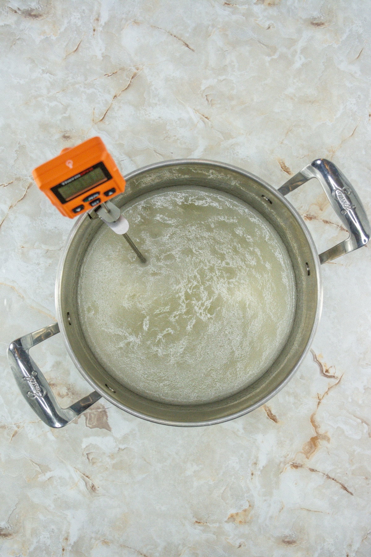 candy being made in a saucepan with a candy thermometer.
