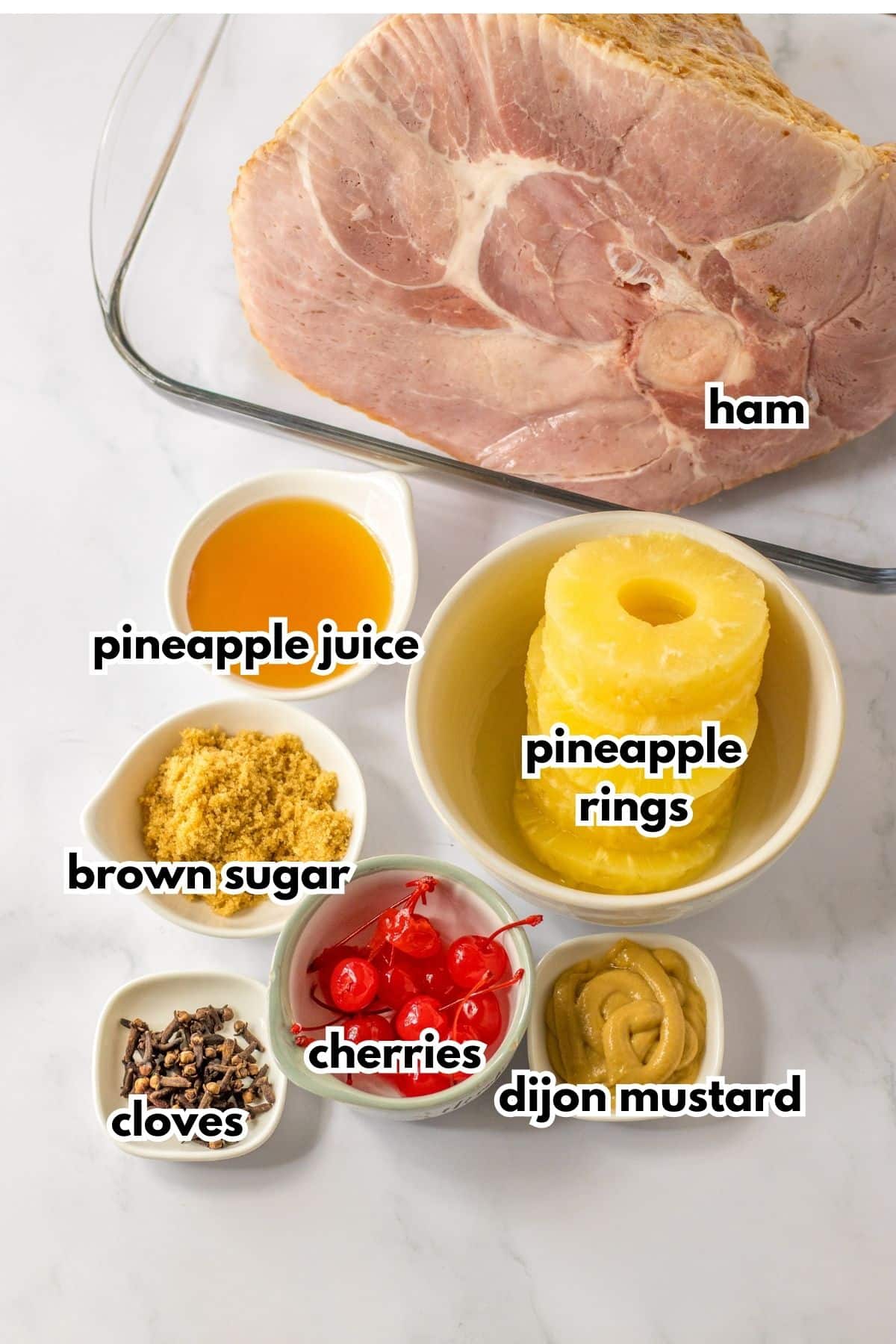 ham in a baking dish, and bowls of pineapple juice, brown sugar, cloves, cherries, dijon mustard, and pineapple rings.