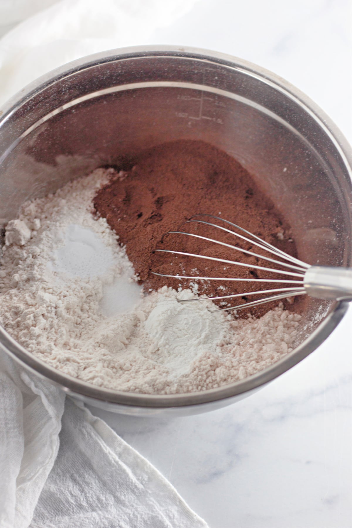 flour, salt, baking powder, and cocoa powder being mixed with a whisk in a mixing bowl.
