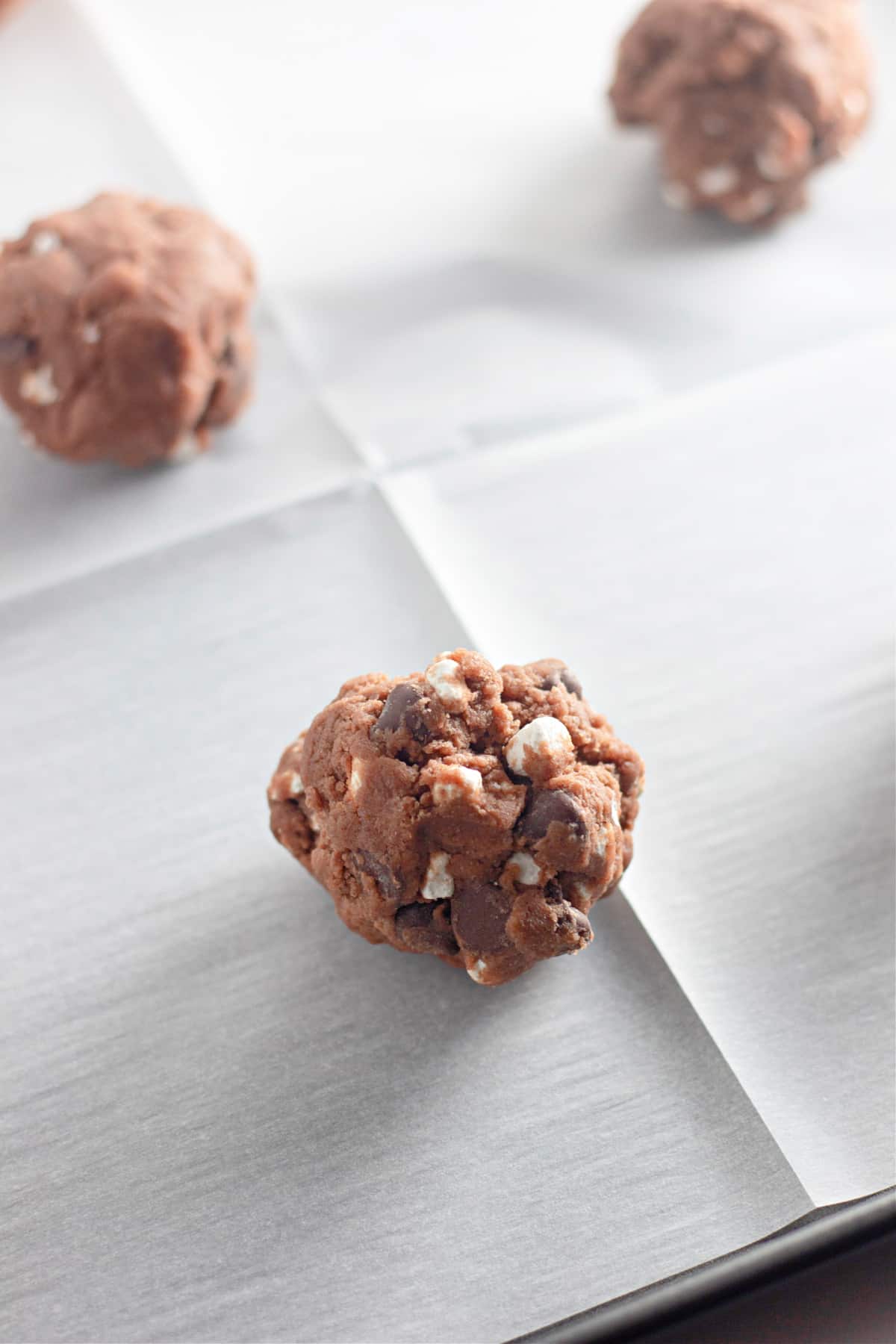 ball of raw cookie dough on a parchment lined baking sheet