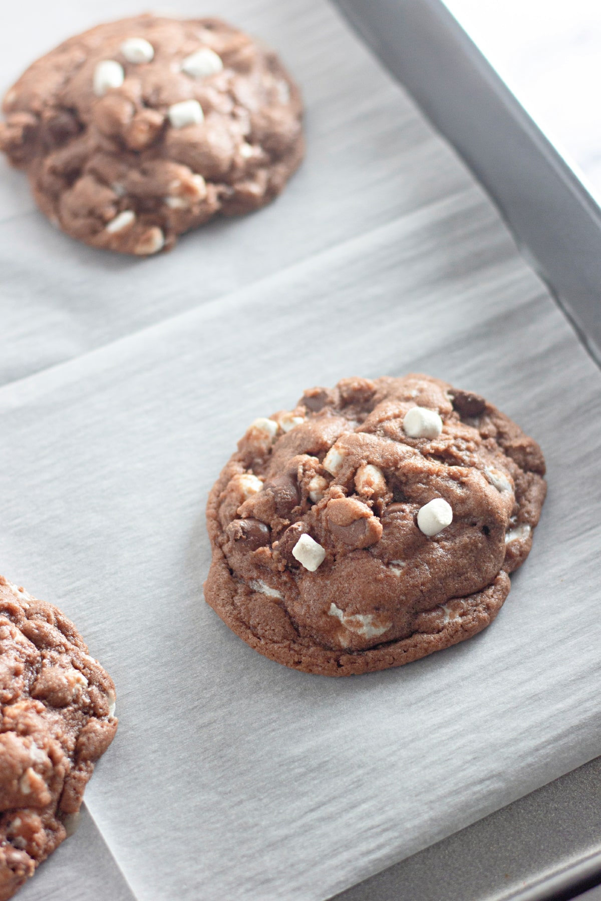 baked hot cocoa cookie on a parchment lined baking sheet.