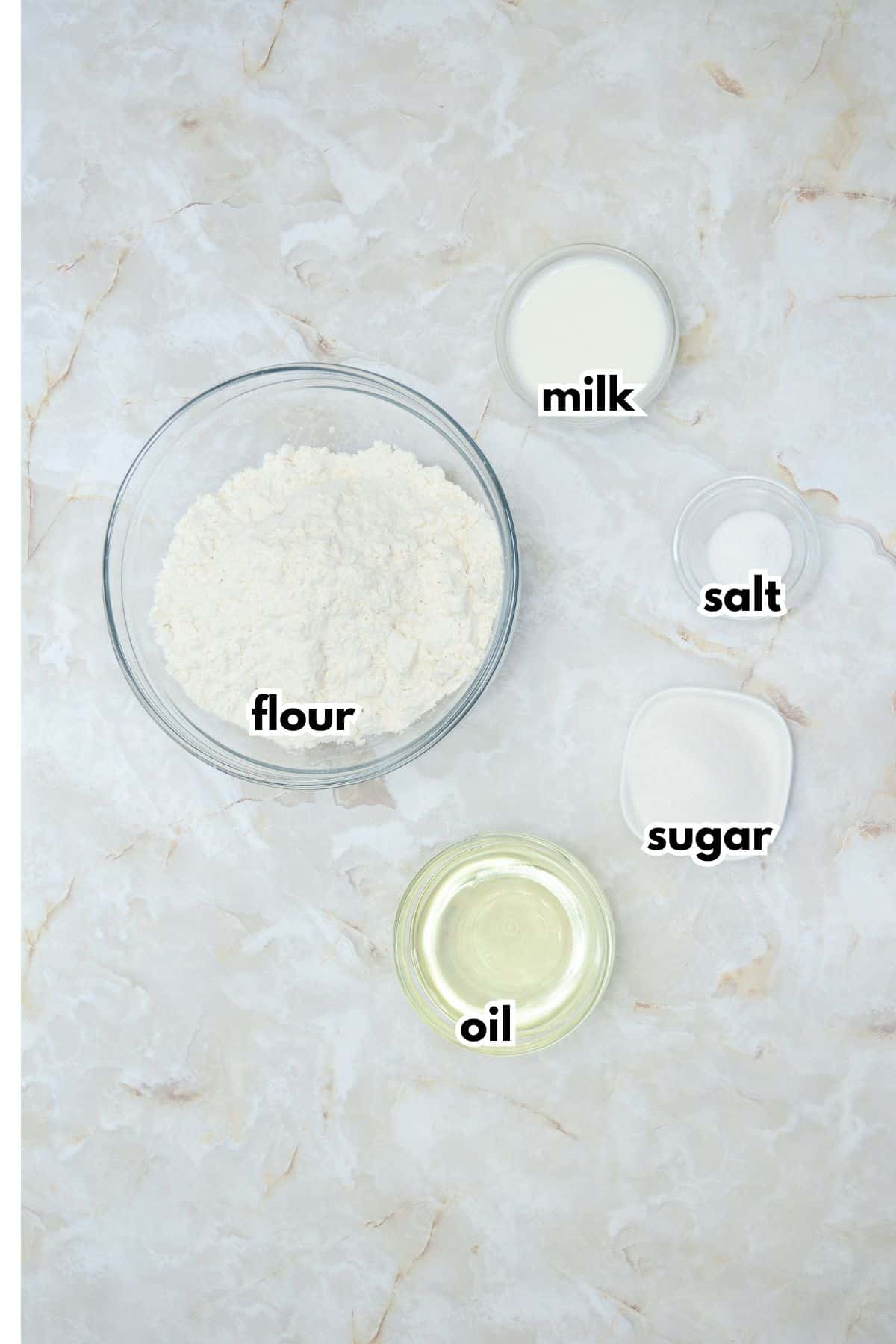 bowls of flour, milk, salt, sugar, and oil.