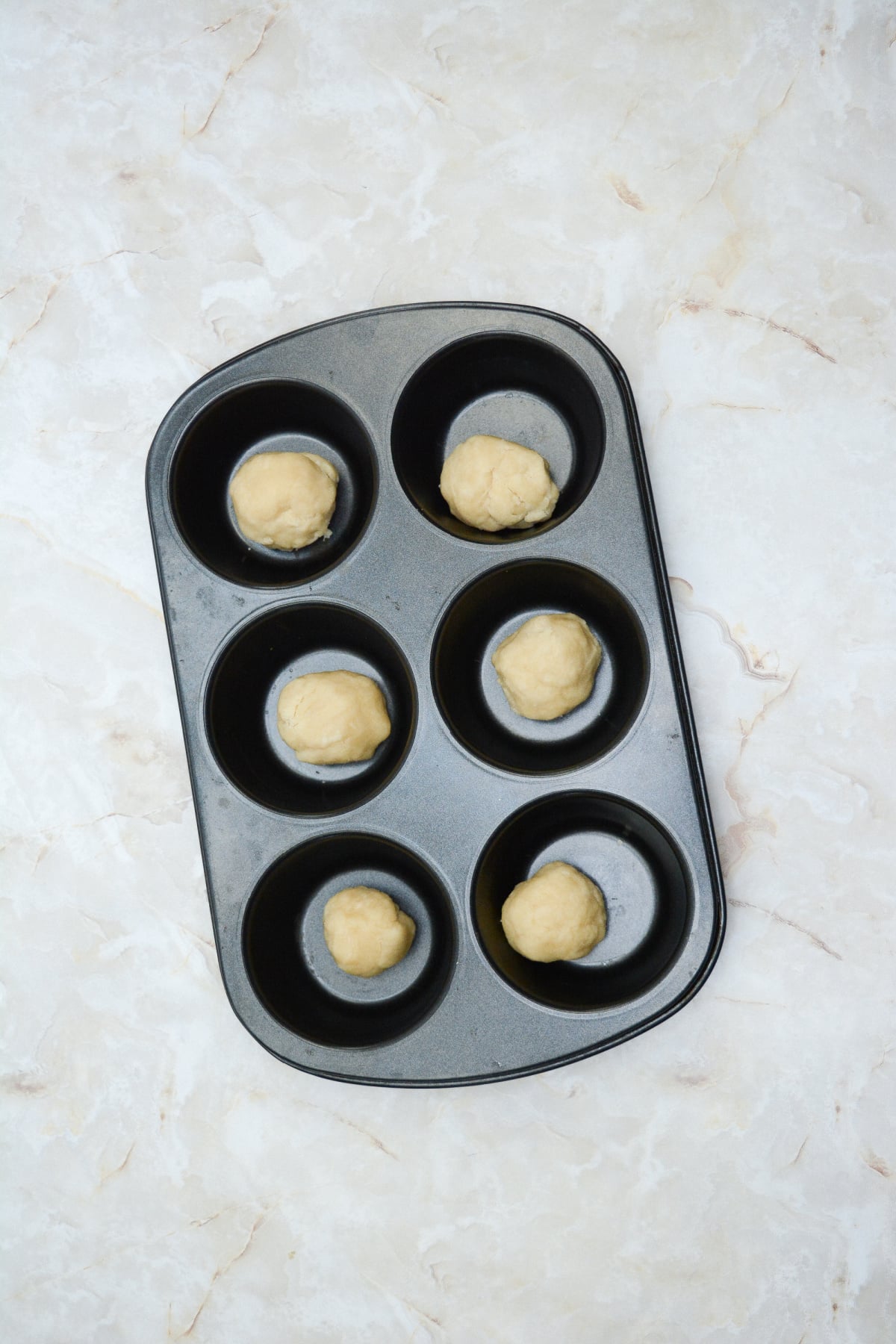 crust being pressed into a muffin tin.