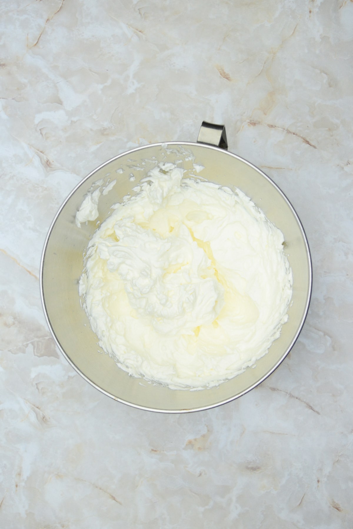 whipped cream in a stainless steel mixing bowl.
