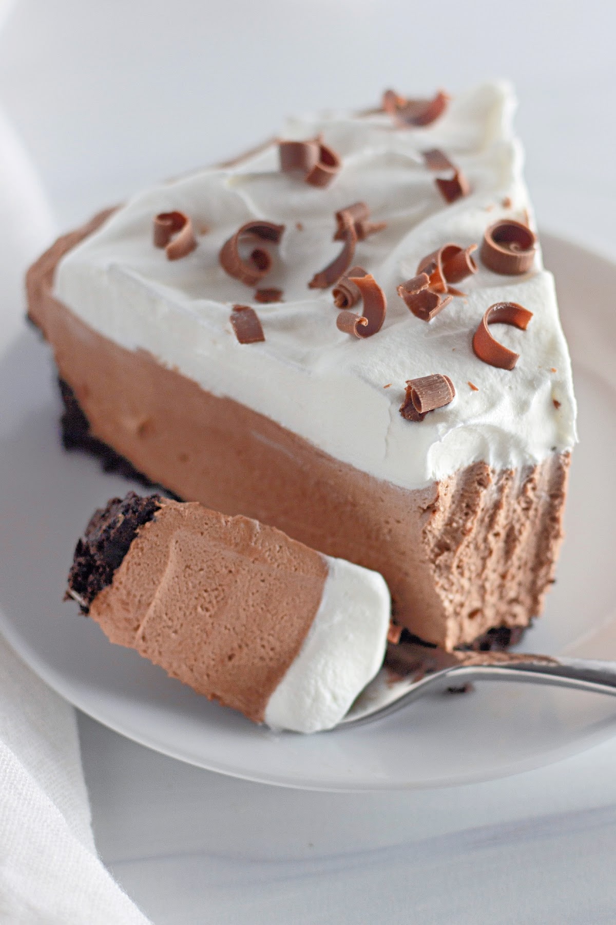 slice of no bake chocolate cheesecake on a plate with a bite missing.