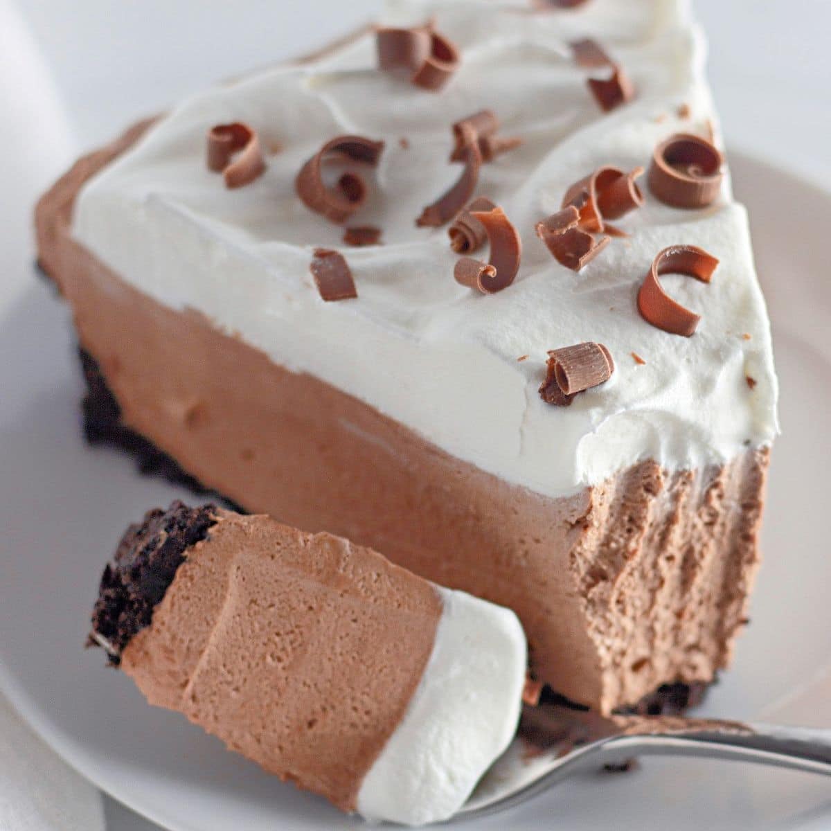 slice of no bake chocolate cheesecake on a plate with a bite missing.