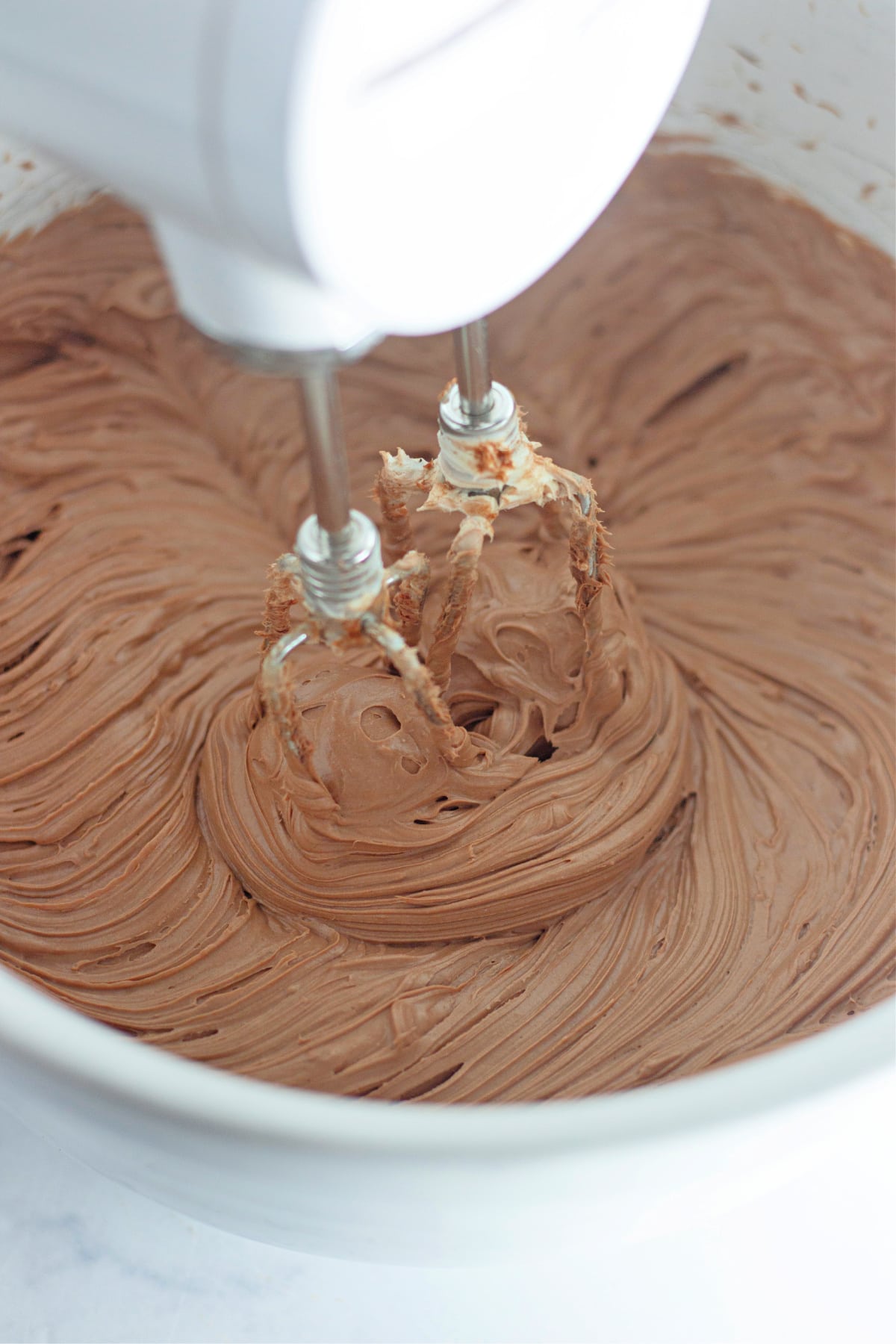 chocolate cheesecake mixture being mixed with a hand mixer.