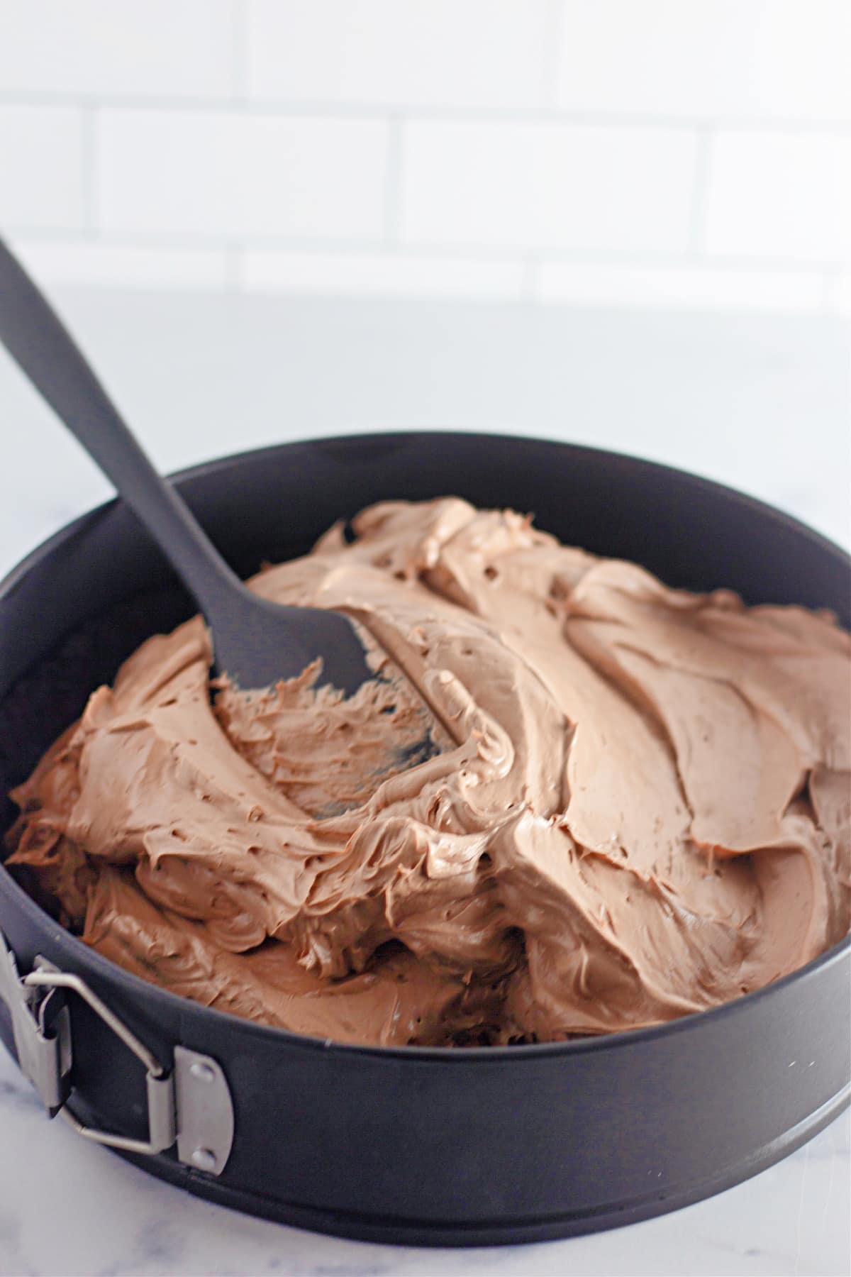 cheesecake mixture being spread on top of the oreo crust.