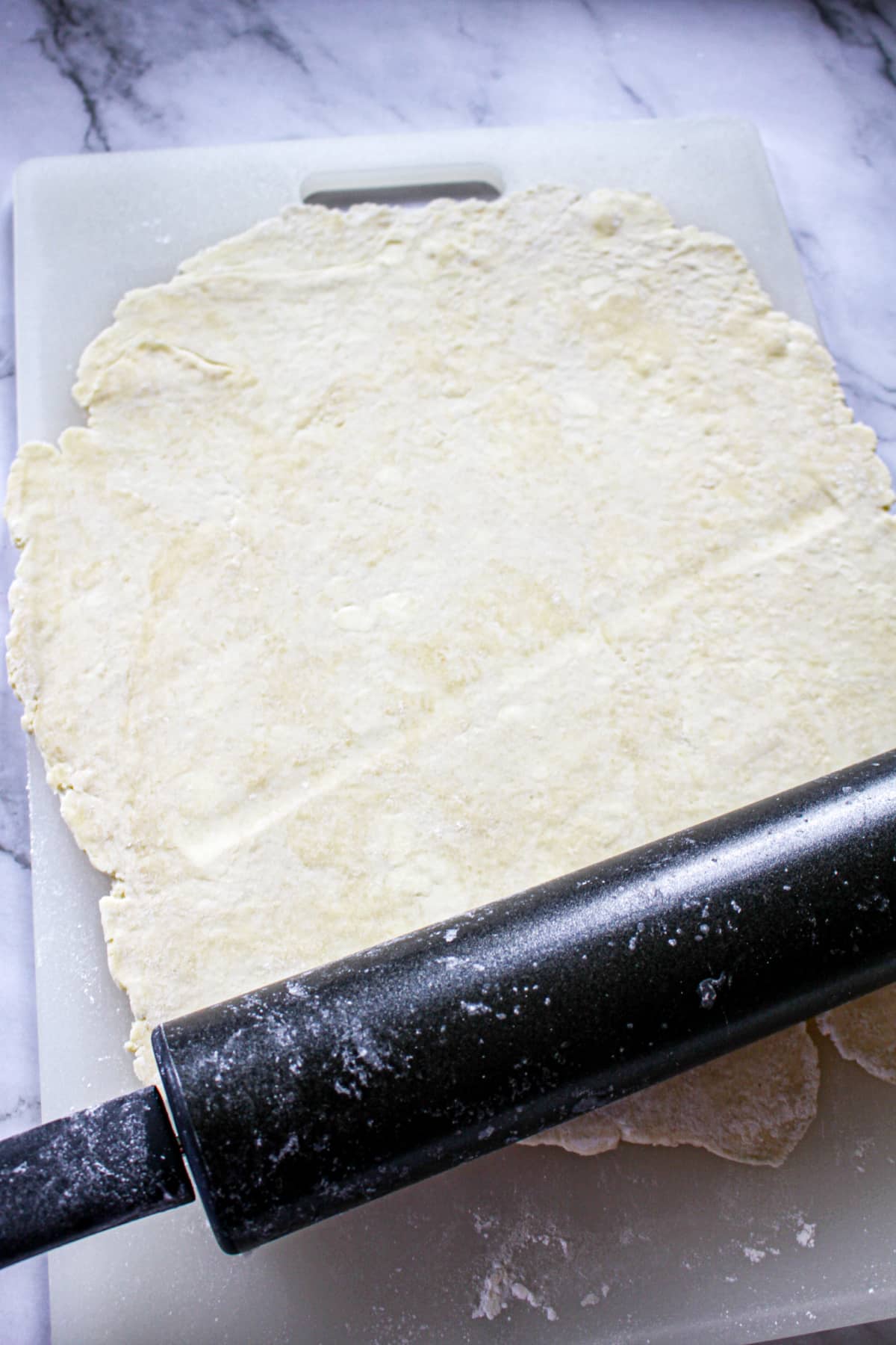 pie crust being rolled out with a rolling pin.