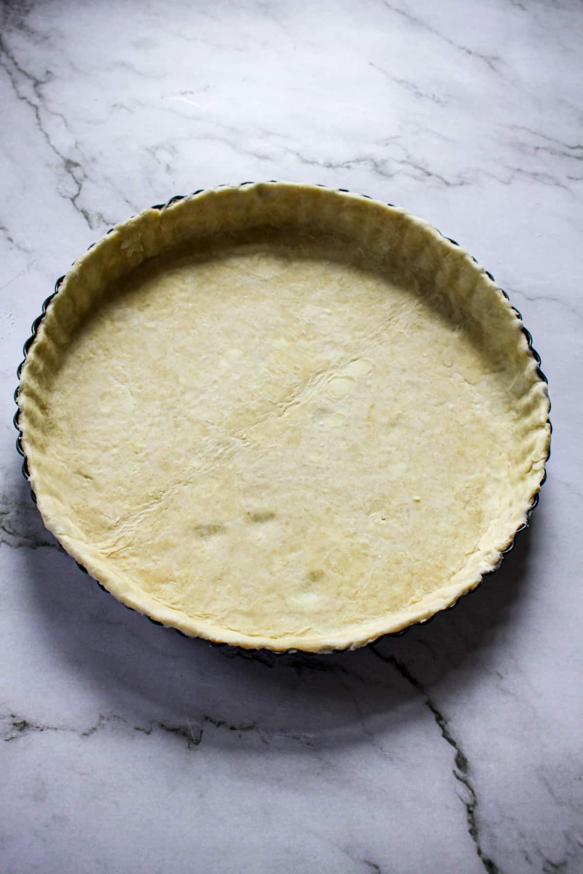pie crust being pressed into a scalloped pie plate.