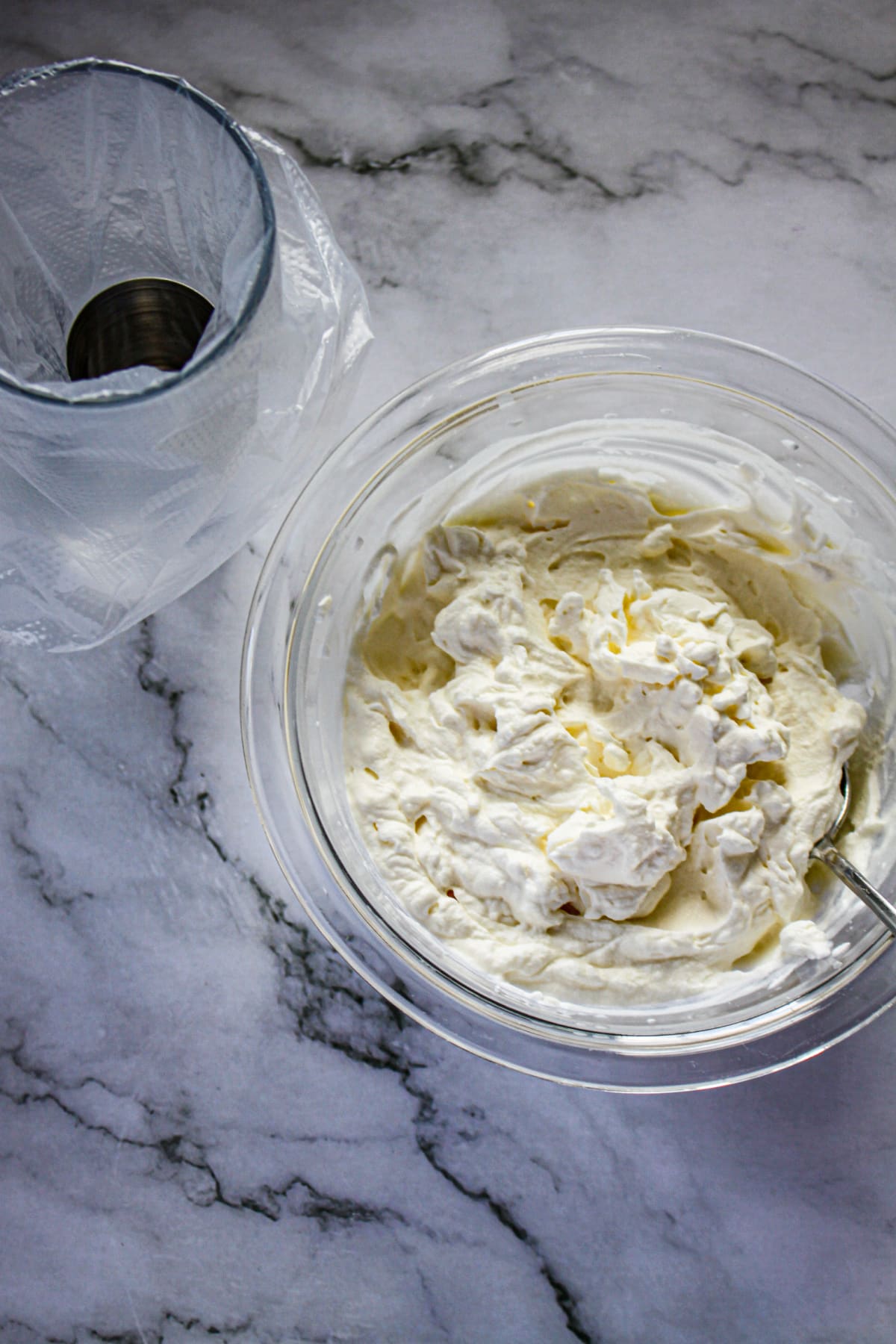 whipped cream being made in a glass mixing bowl.