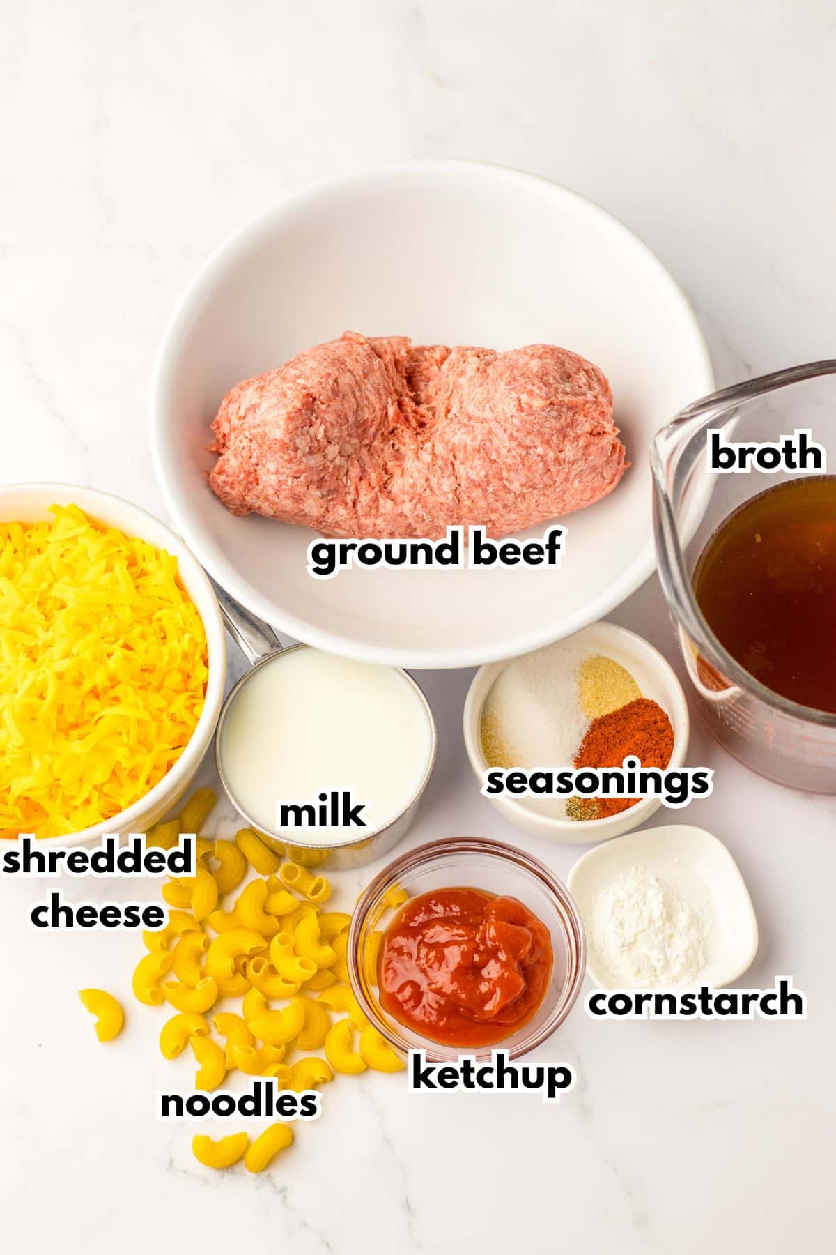 bowls of ground beef, shredded cheese, noodles, milk, seasonings, ketchup, cornstarch, and broth.