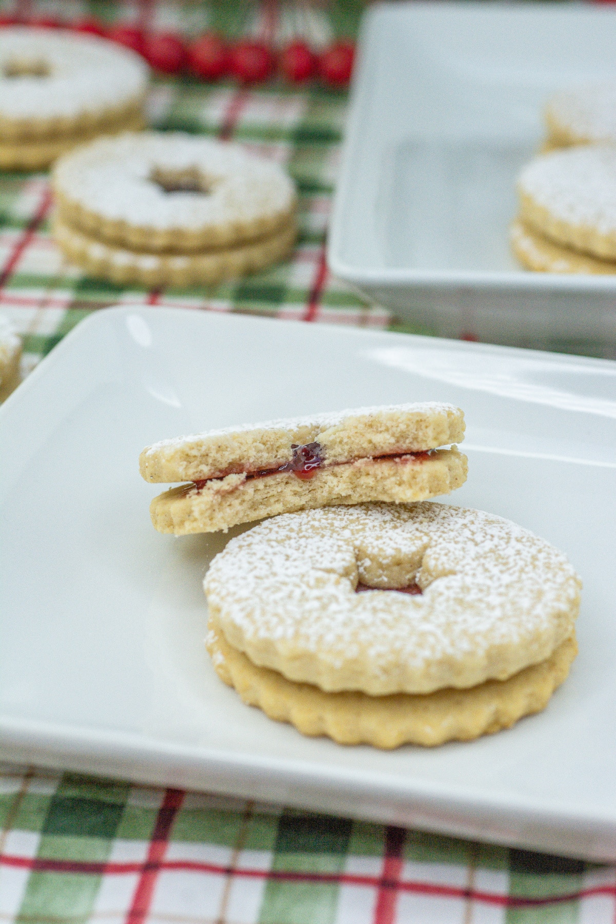 two raspberry linzer cookies on a plate.