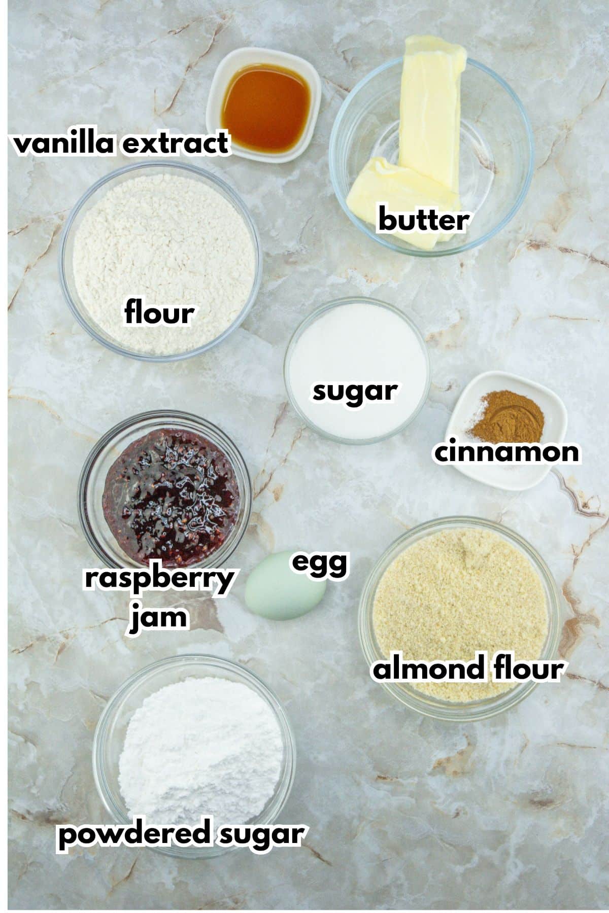 bowls of vanilla extract, butter, flour, sugar, cinnamon, raspberry jam, egg, almond flour, and powdered sugar.