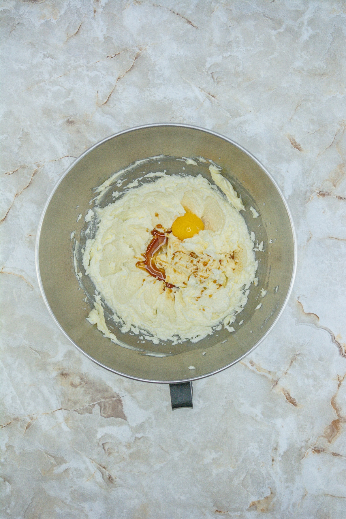 butter, sugar, eggs, and vanilla extract being mixed in a stand mixer.