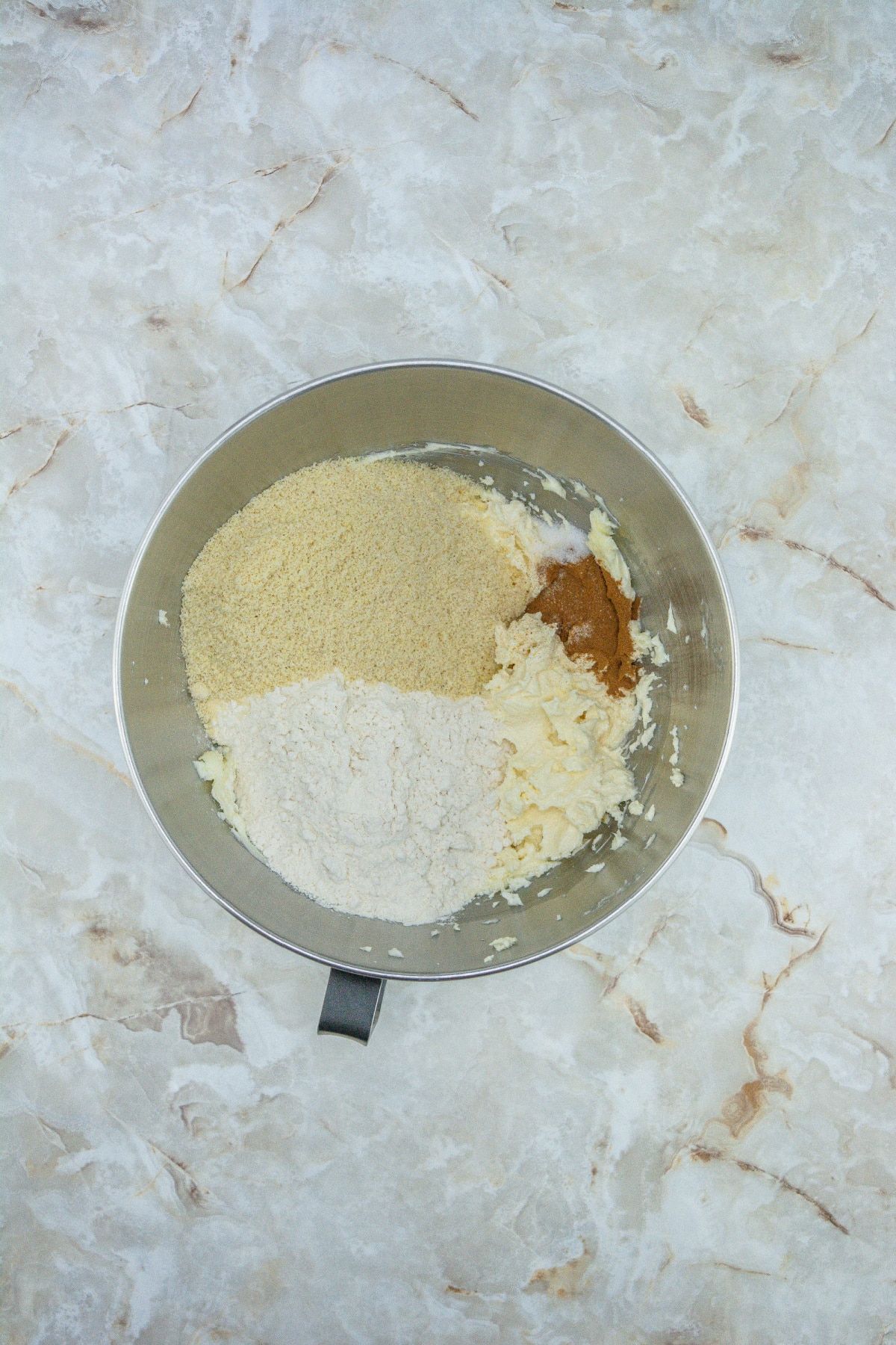 dry ingredients being added to the cookie dough in a stand mixer.