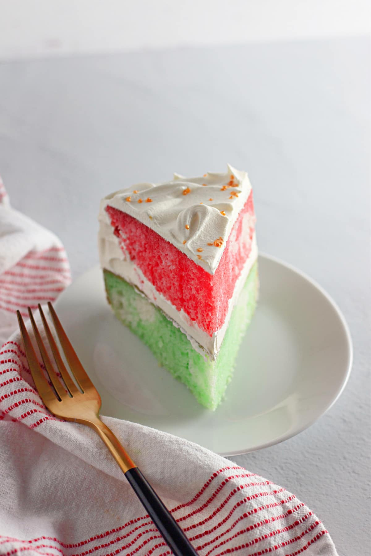 slice of red and green christmas cake on a white plate.