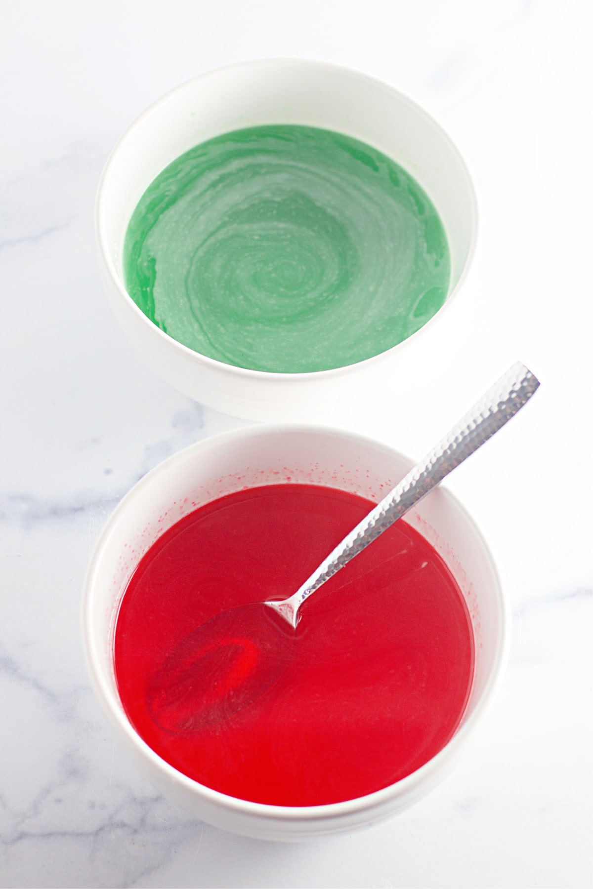 bowls of red and green jello mixed with water.