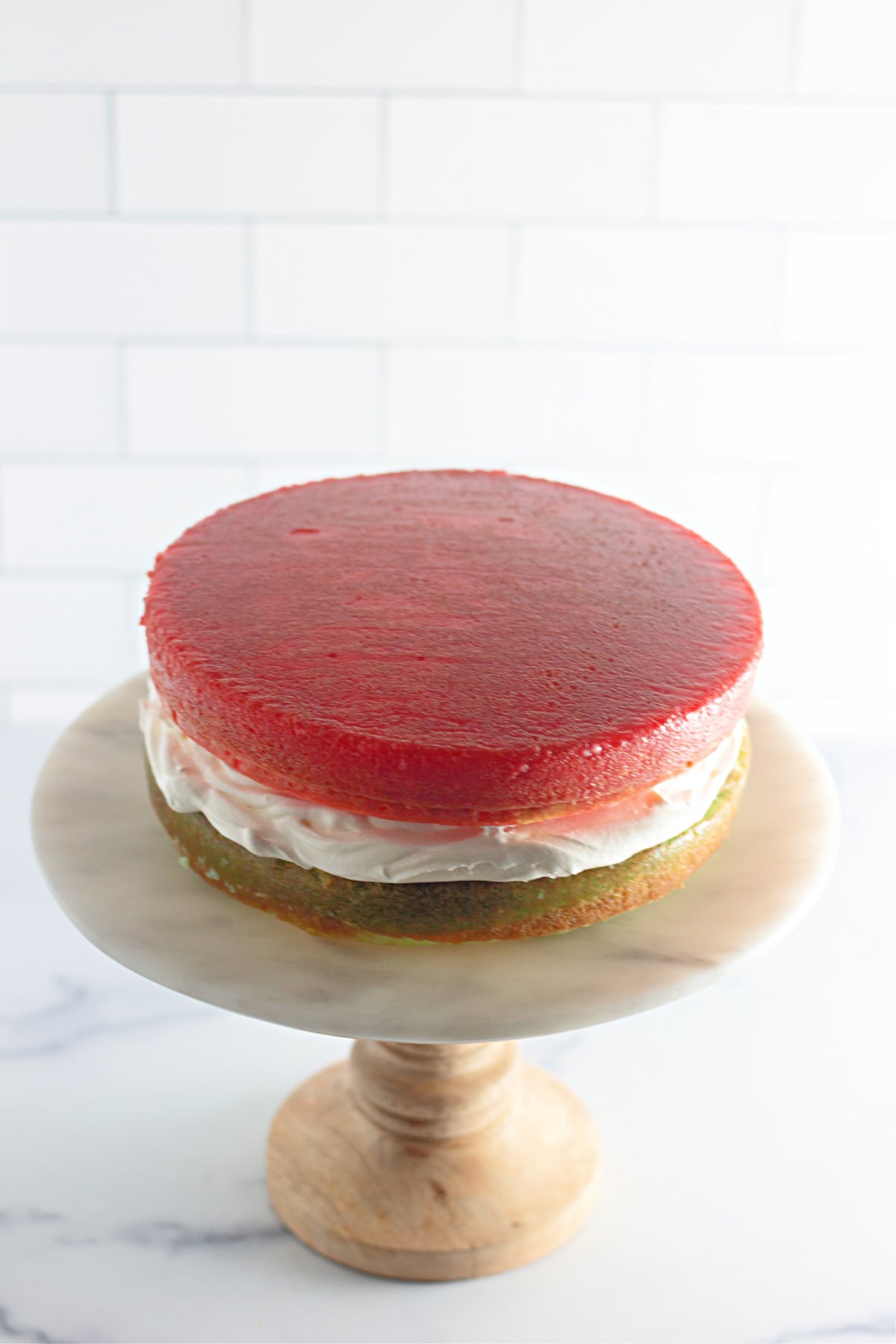 red and green cake layers being spread with frosting.