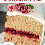 slice of spice cake with cranberry filling topped with sugared cranberries on a plate.