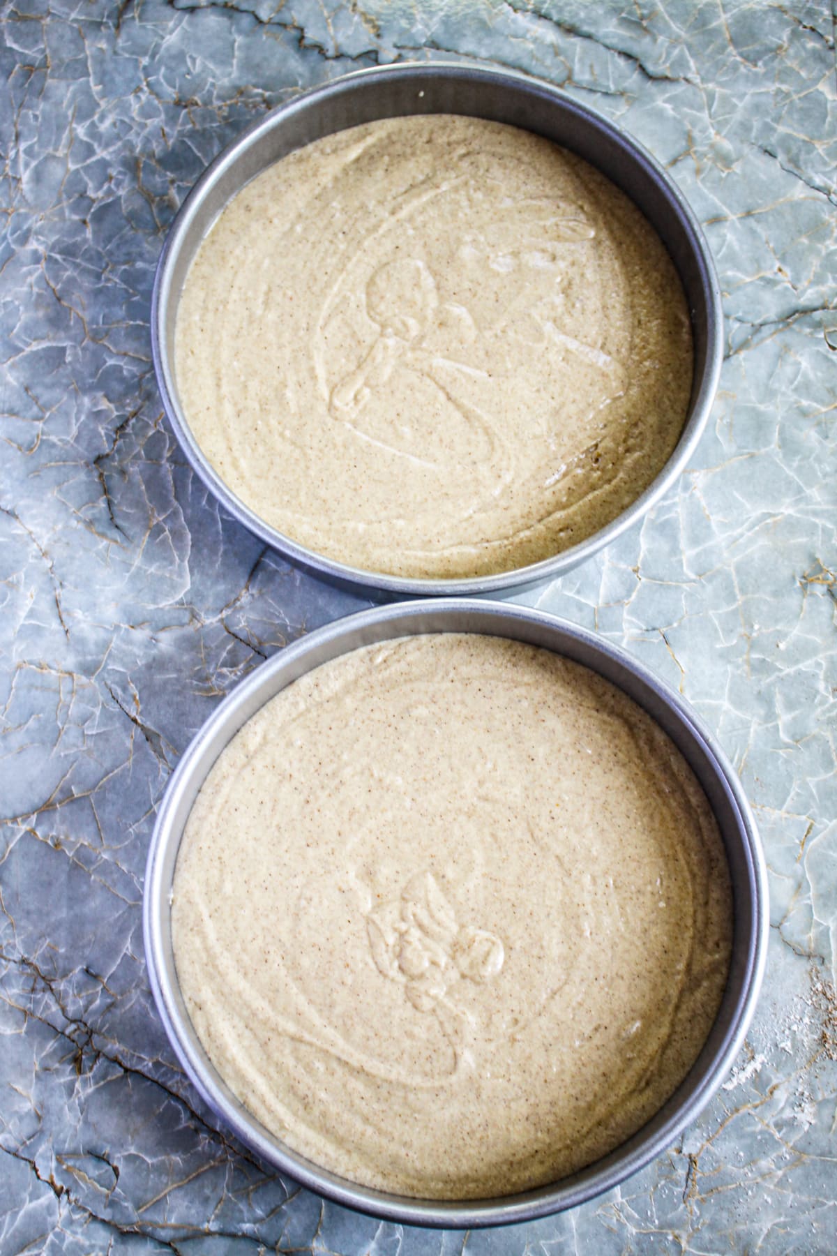spice cake batter in two round cake pans ready for the oven.