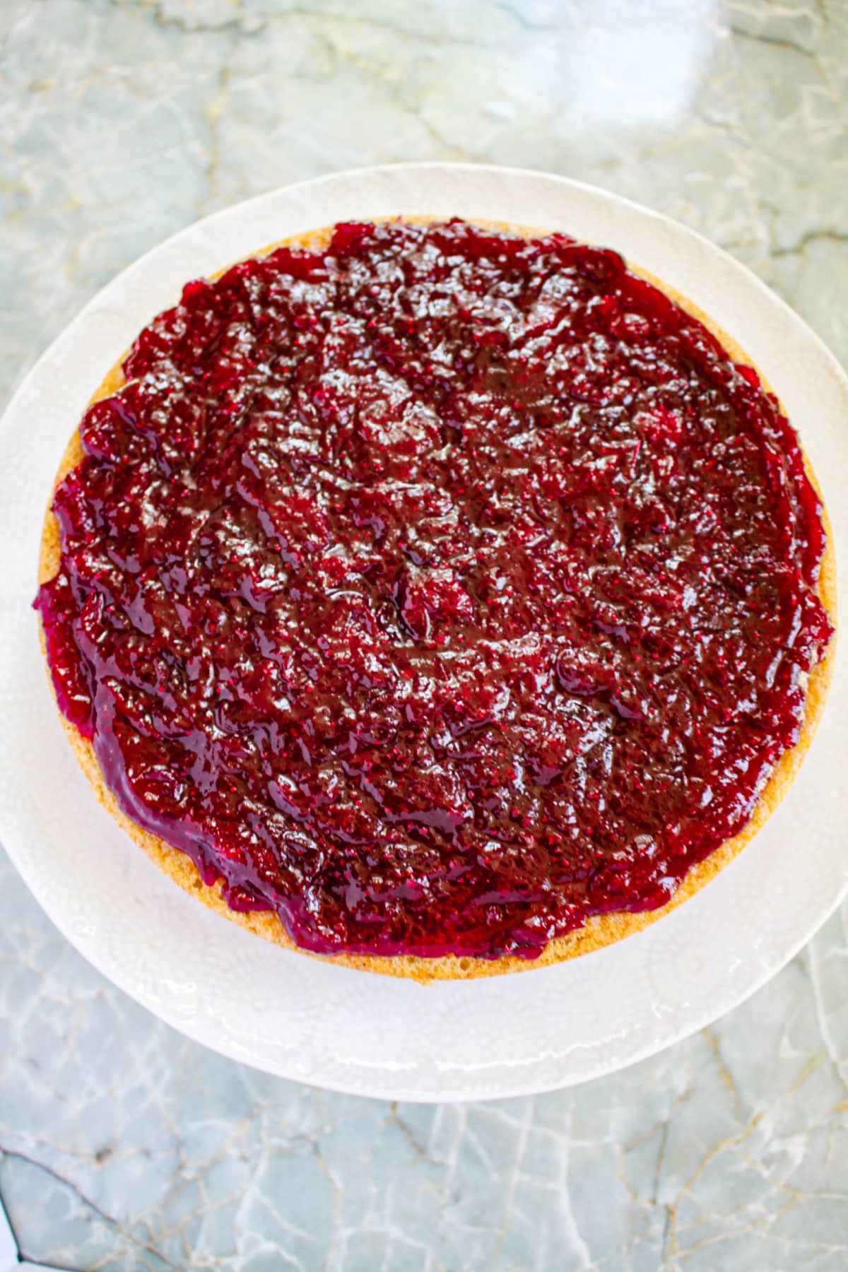 cranberry filling being spread on top of a cake layer.