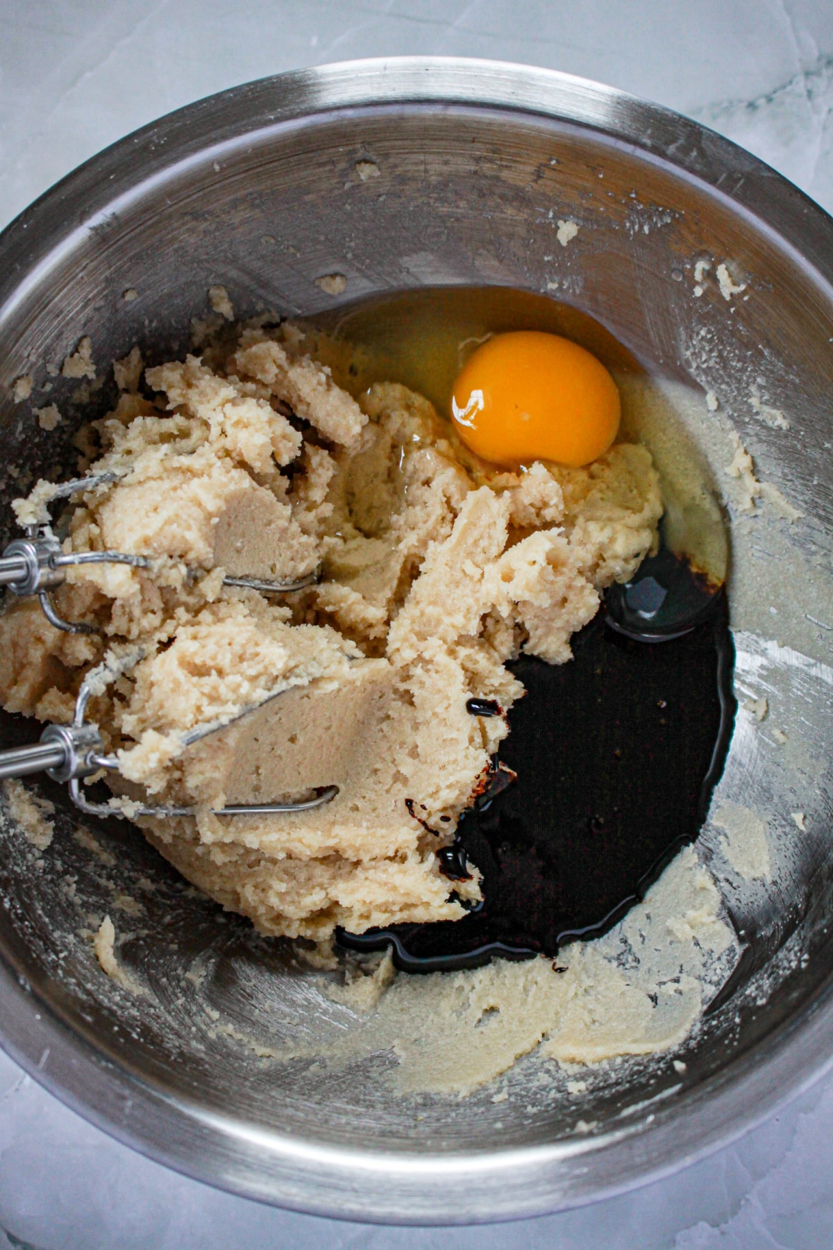 butter, sugar, eggs, and molasses being mixed in mixing bowl with a hand mixer.