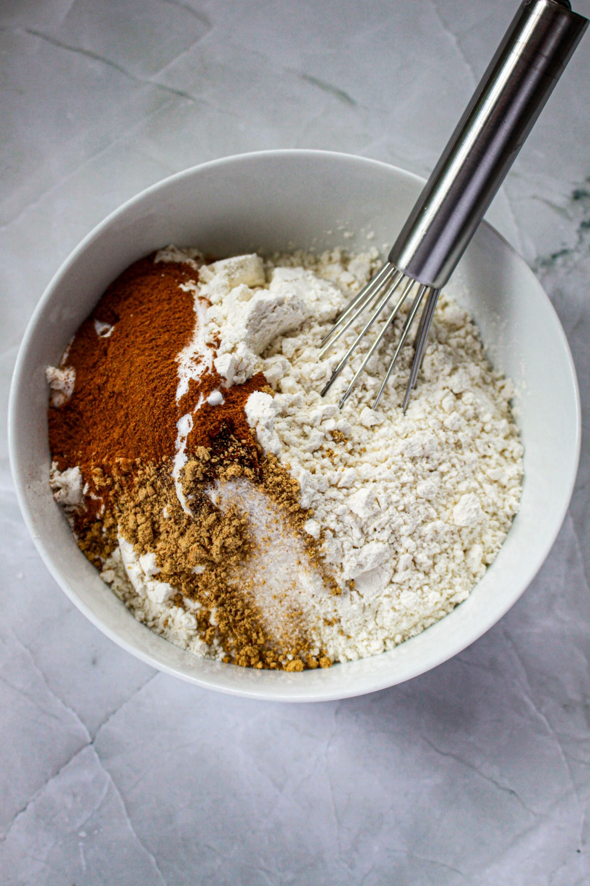 flour, spice, salt, and baking powder being mixed with a whisk in a small bowl.