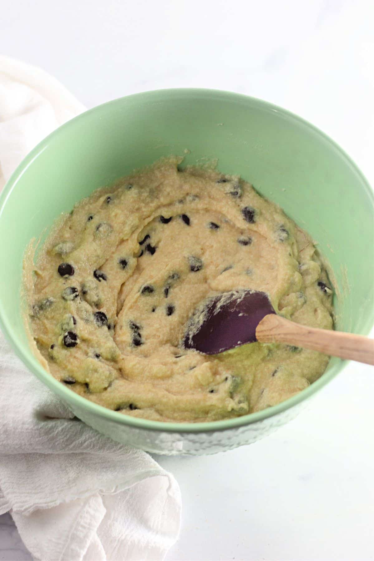 chocolate chips being folded into banana muffin batter.