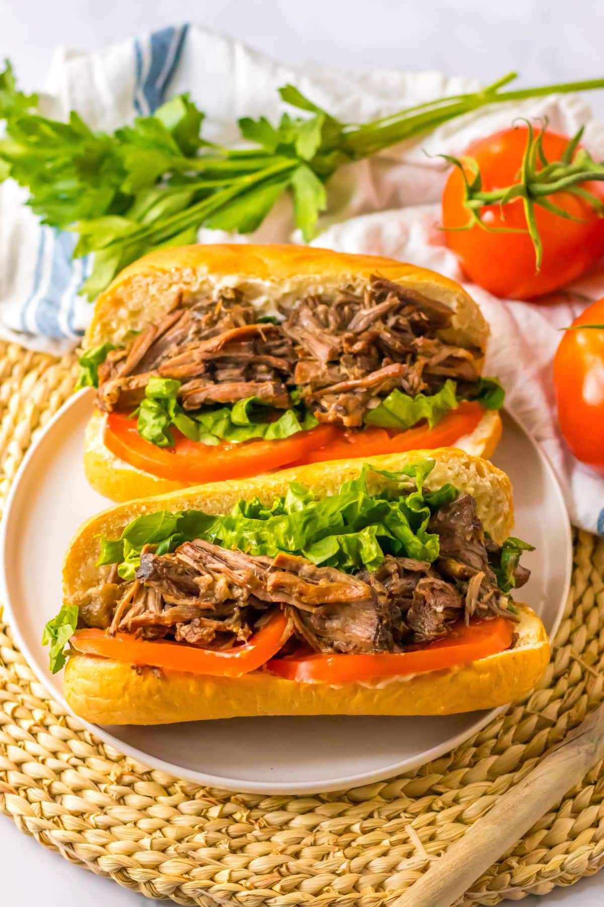two slow cooker beef po boy sandwiches on a plate.