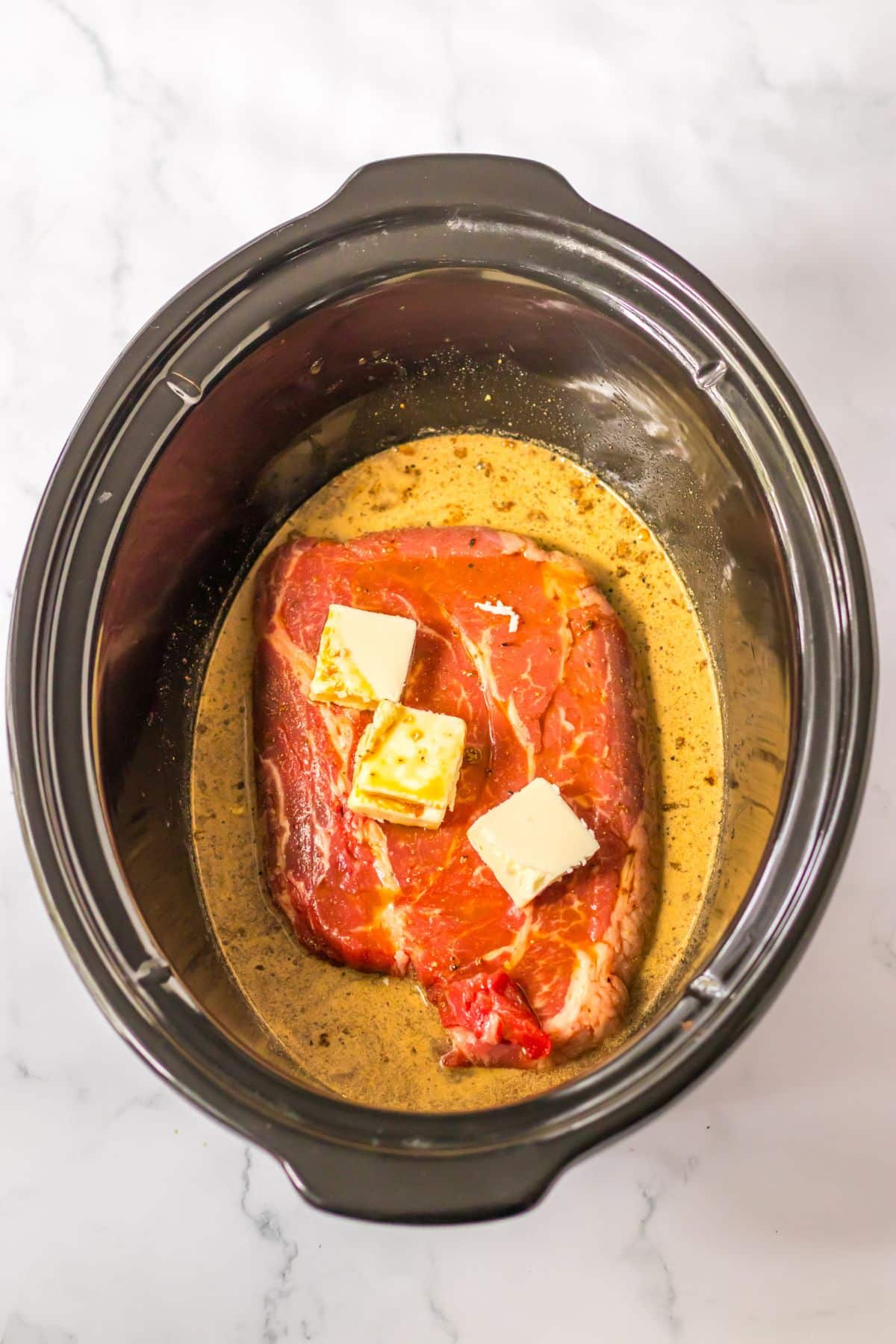 raw beef roast, gravy mix, and butter in a slow cooker.