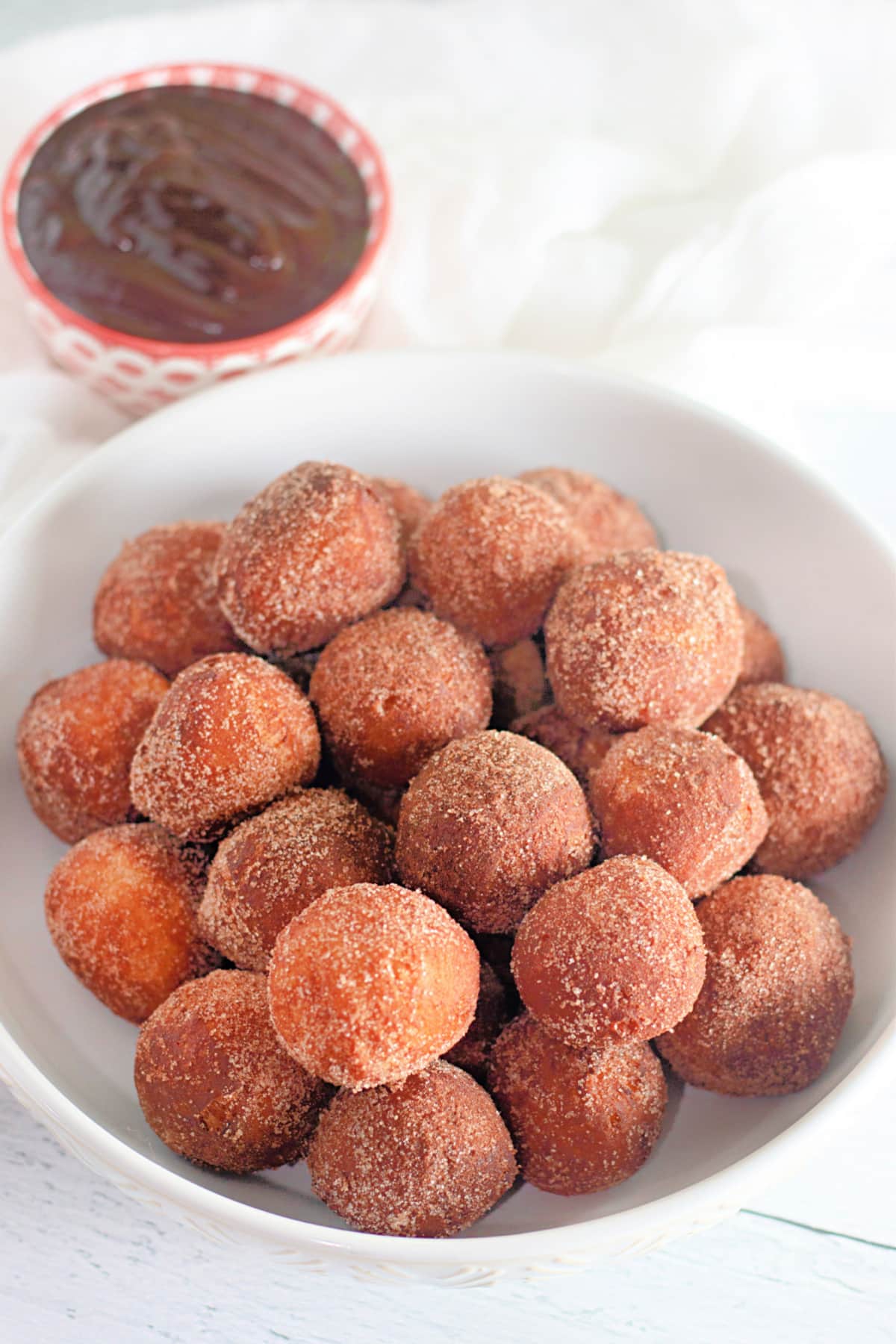 donut holes from biscuit dough coated in a cinnamon sugar in a white bowl.
