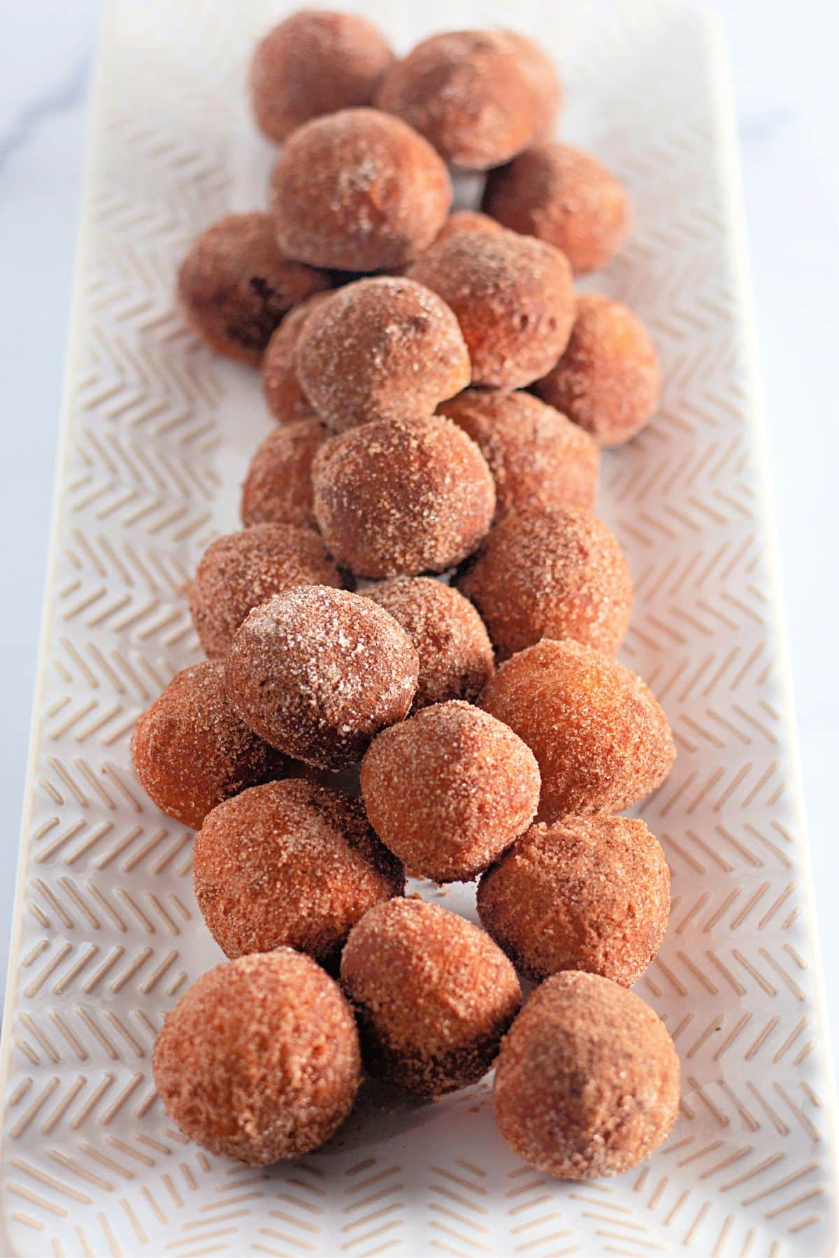donut holes from biscuit dough coated in a cinnamon sugar on a platter.