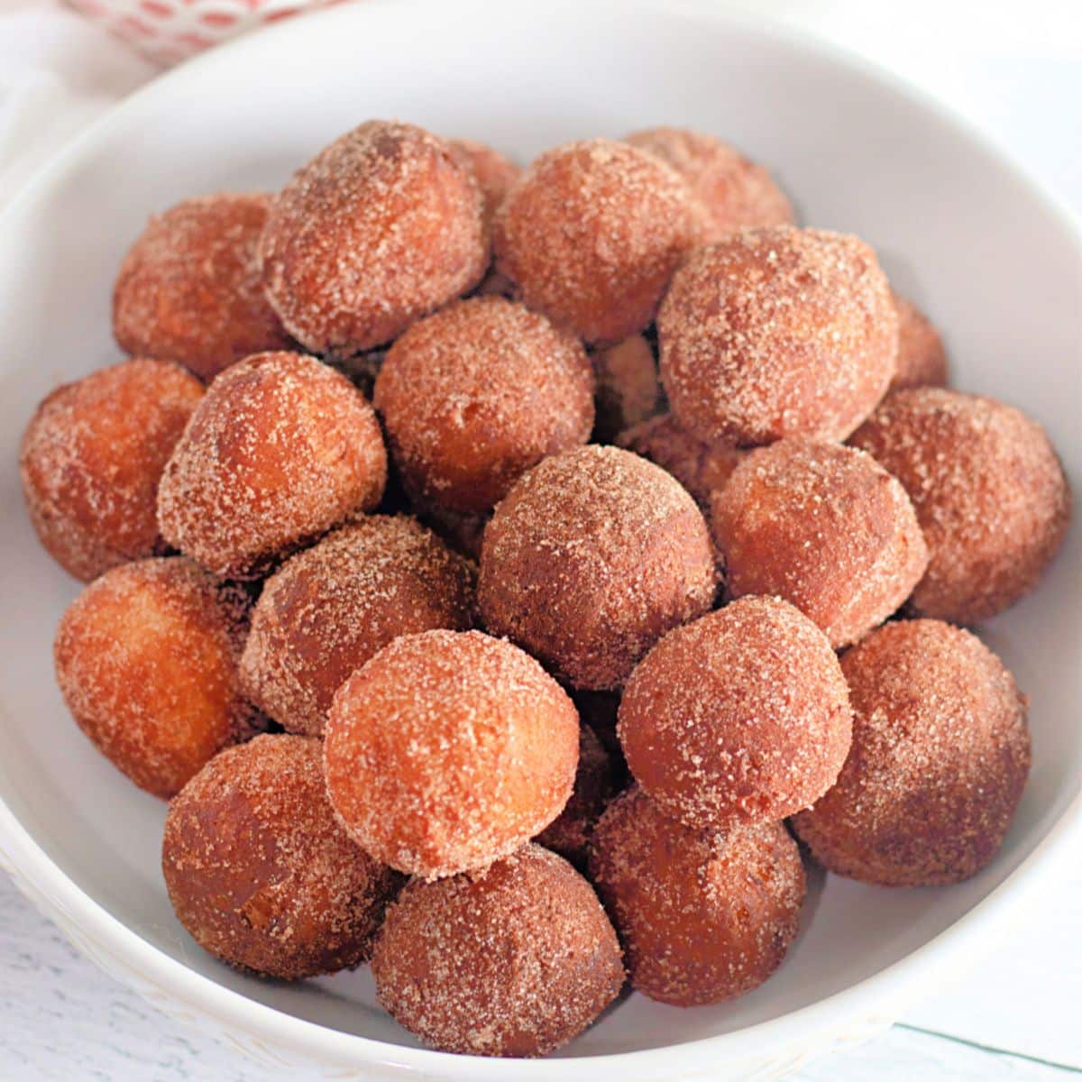 donut holes from biscuit dough coated in a cinnamon sugar in a white bowl.