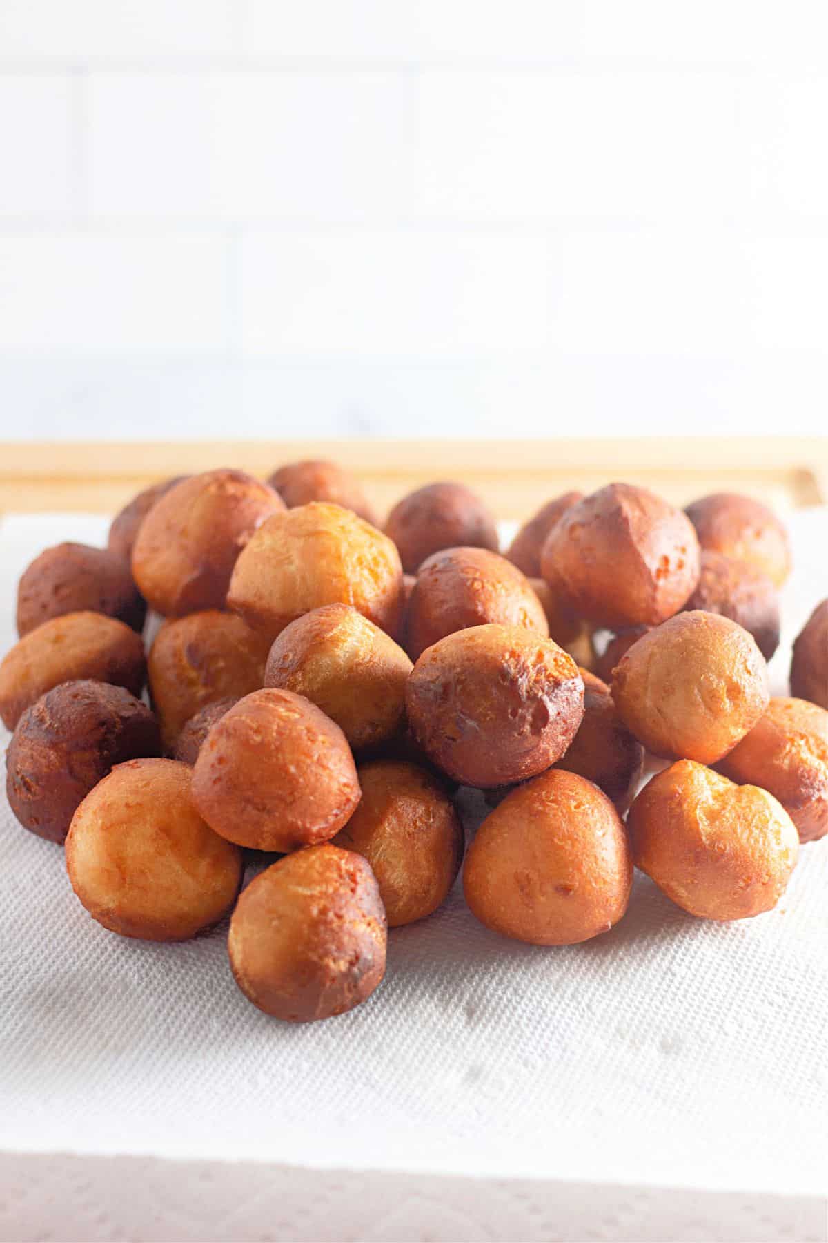 fried donut holes drying on a paper towel.