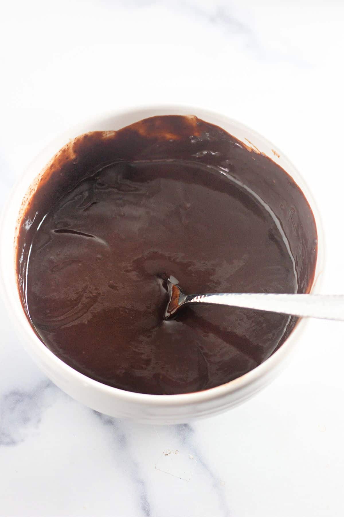 bowl and spoon filled with homemade chocolate sauce.
