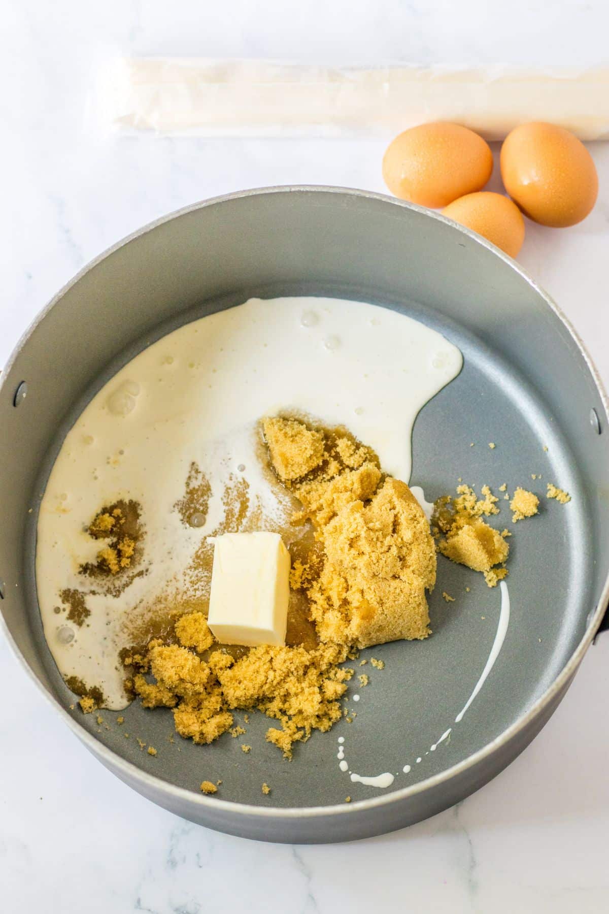 cream, brown sugar, and butter being melted in a saucepan,