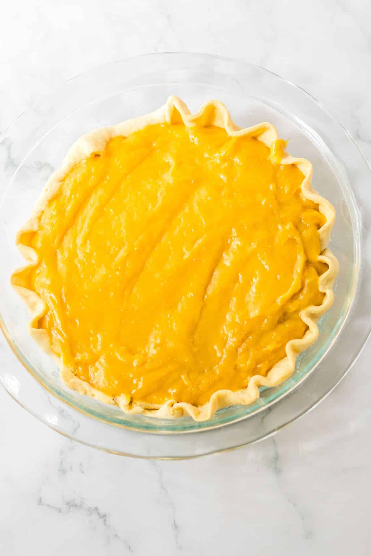 butterscotch filling being added to a baked pie crust.