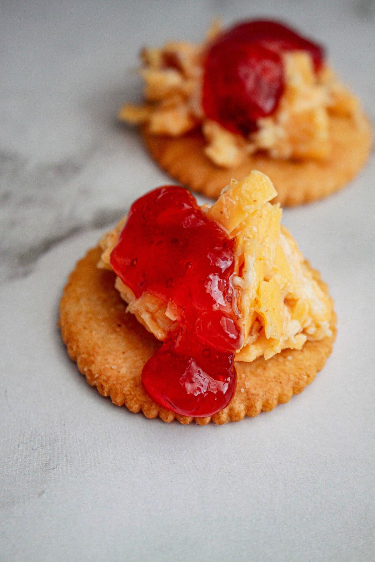 bite of cheese ring and jam on a cracker.