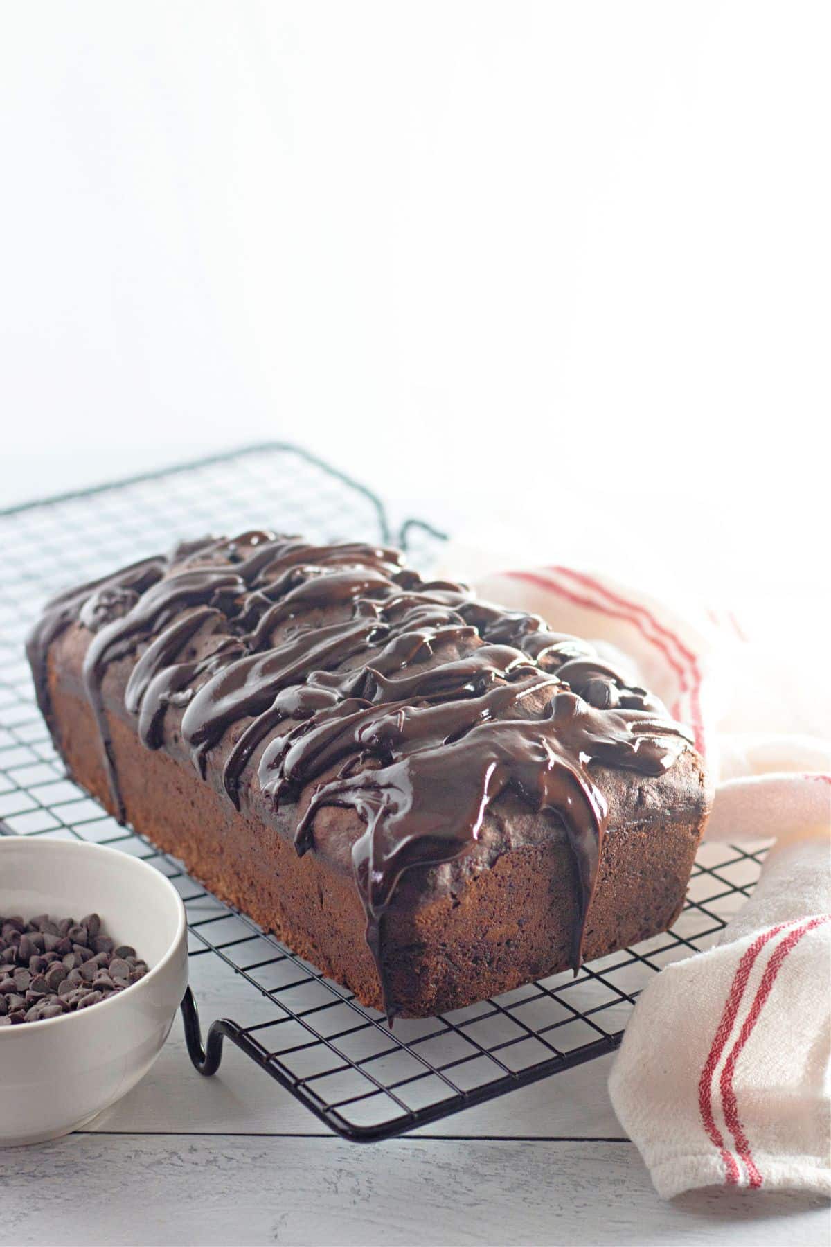 uncut loaf of triple chocolate banana bread on a wire cooling rack.