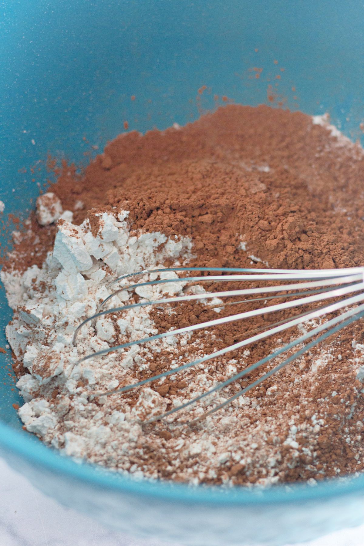 cocoa powder, flour, and salt being whisked in a mixing bowl.