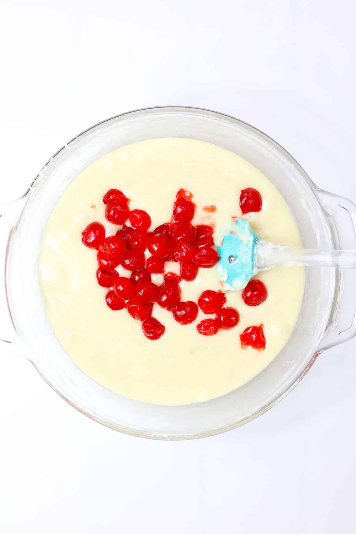 cherries being mixed into melted white chocolate.