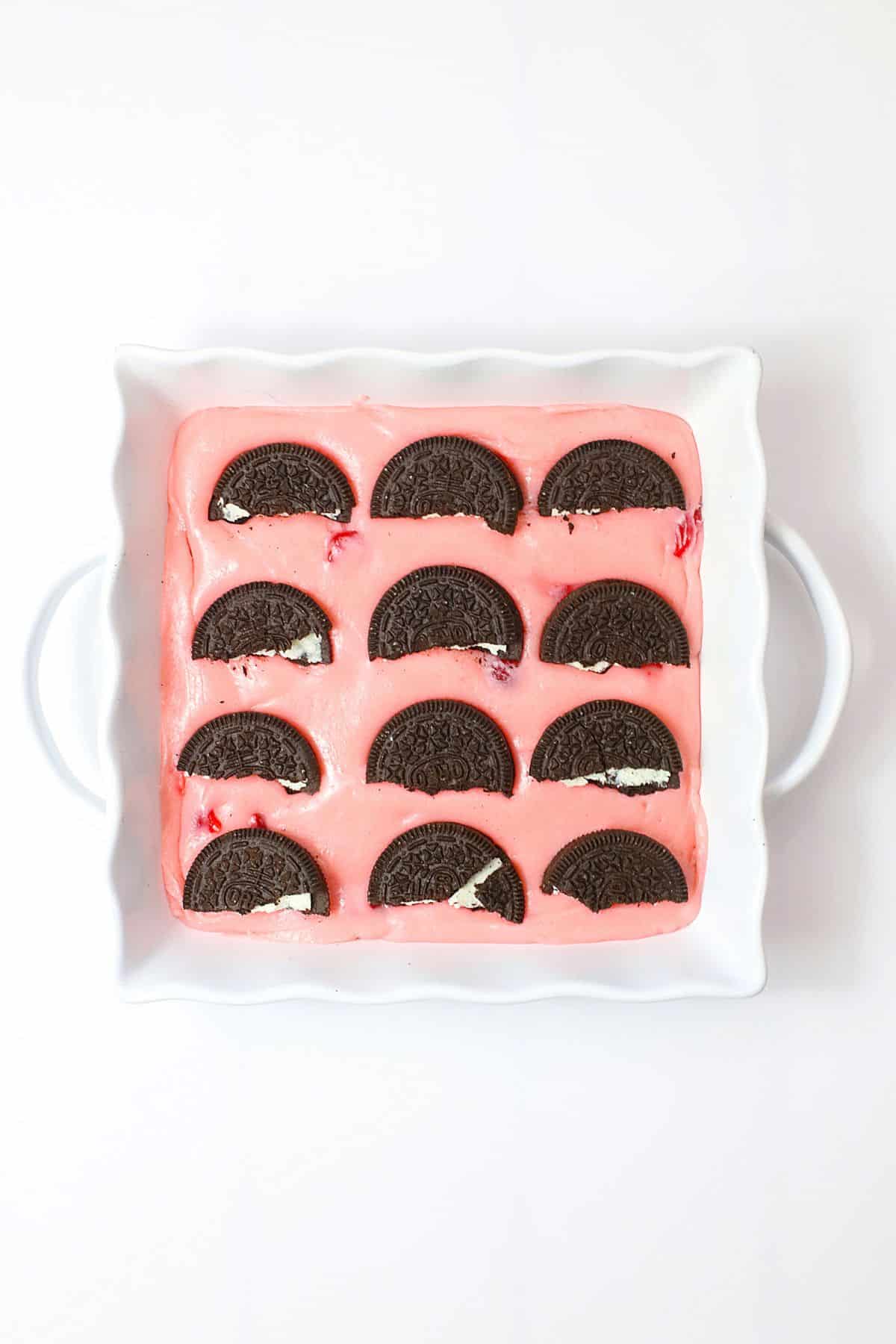 Oreo cookies being placed on top of cherry fudge.