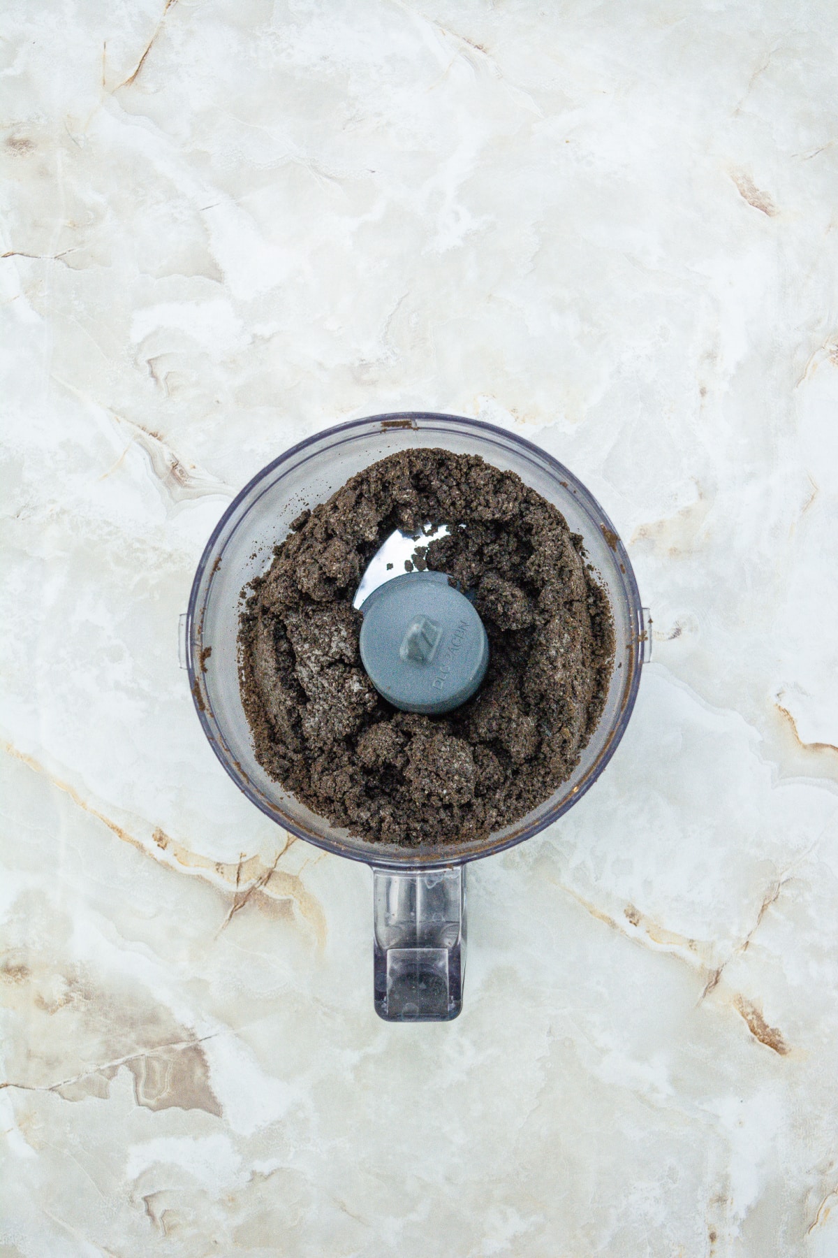 Oreo cookies being crushed in a food processor.