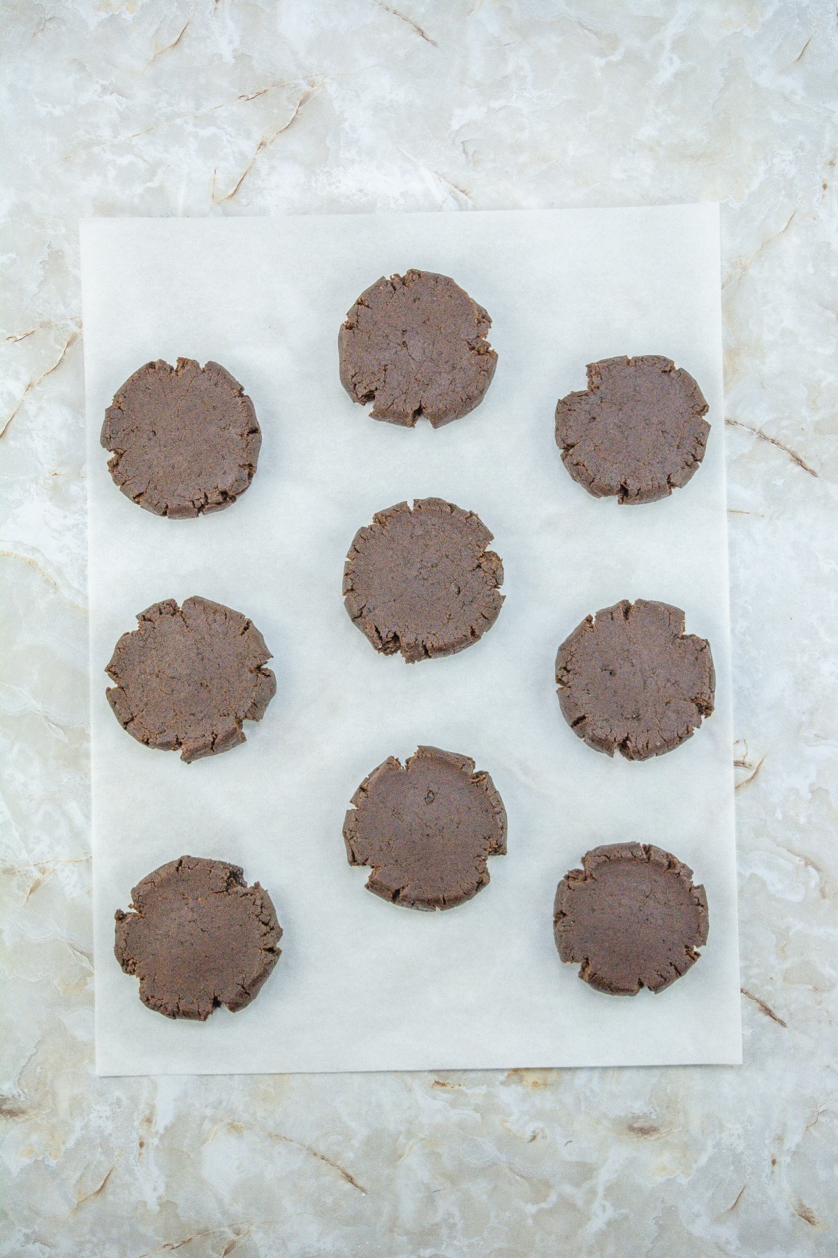 baked cookies being flattened with a piece of parchment paper.