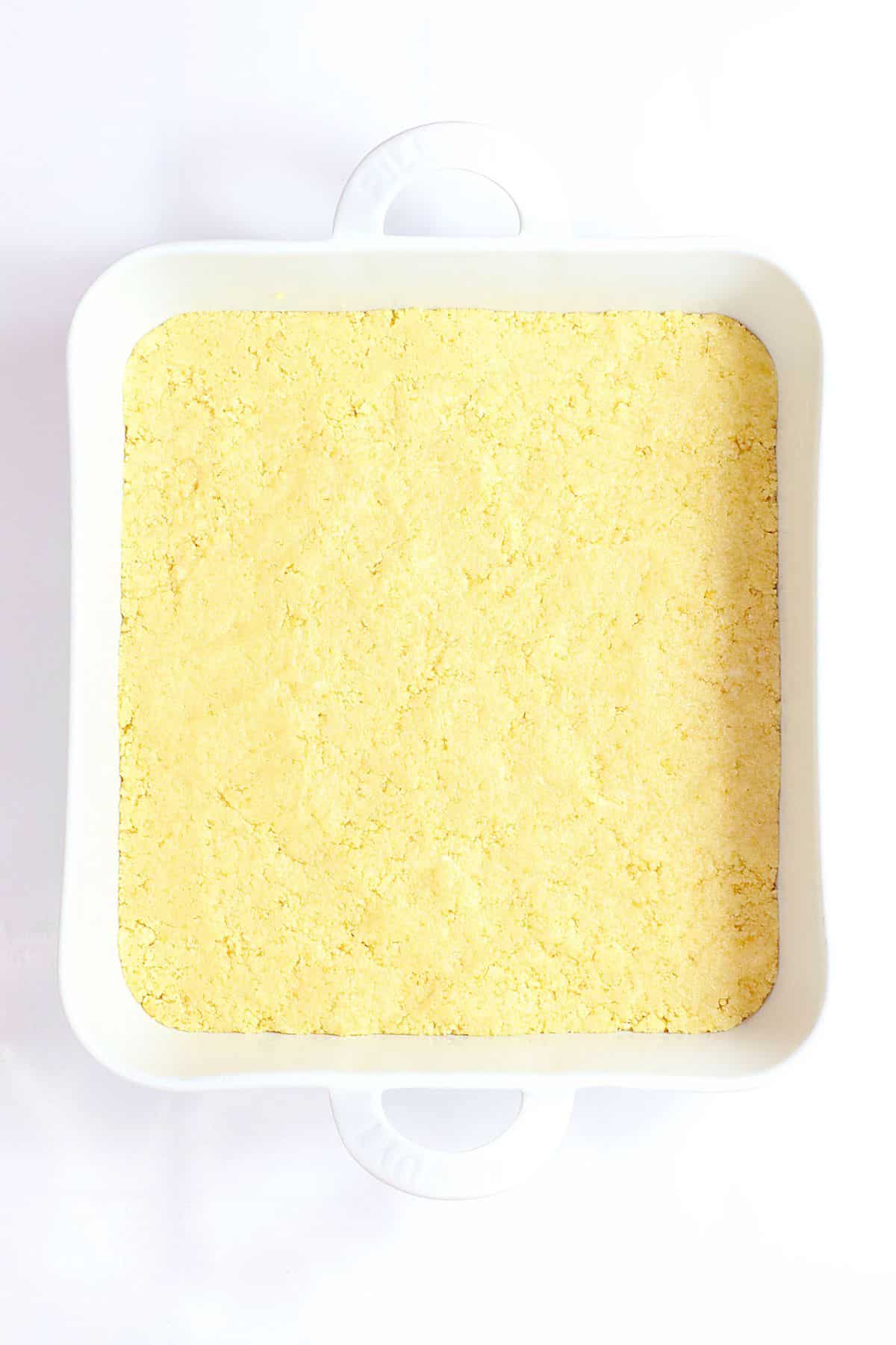 Oreo crust being pressed into a casserole dish.