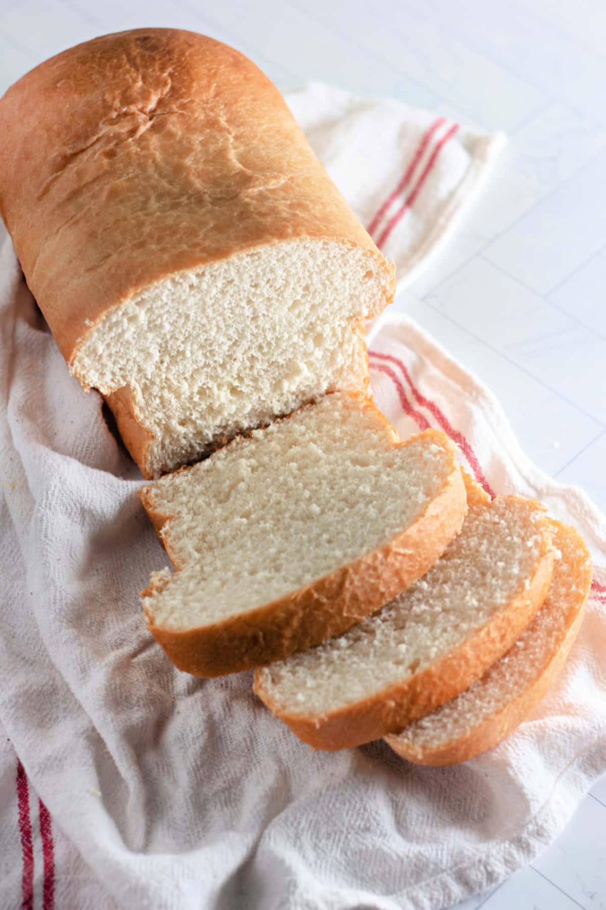 country white bread loaf with three slices cut.