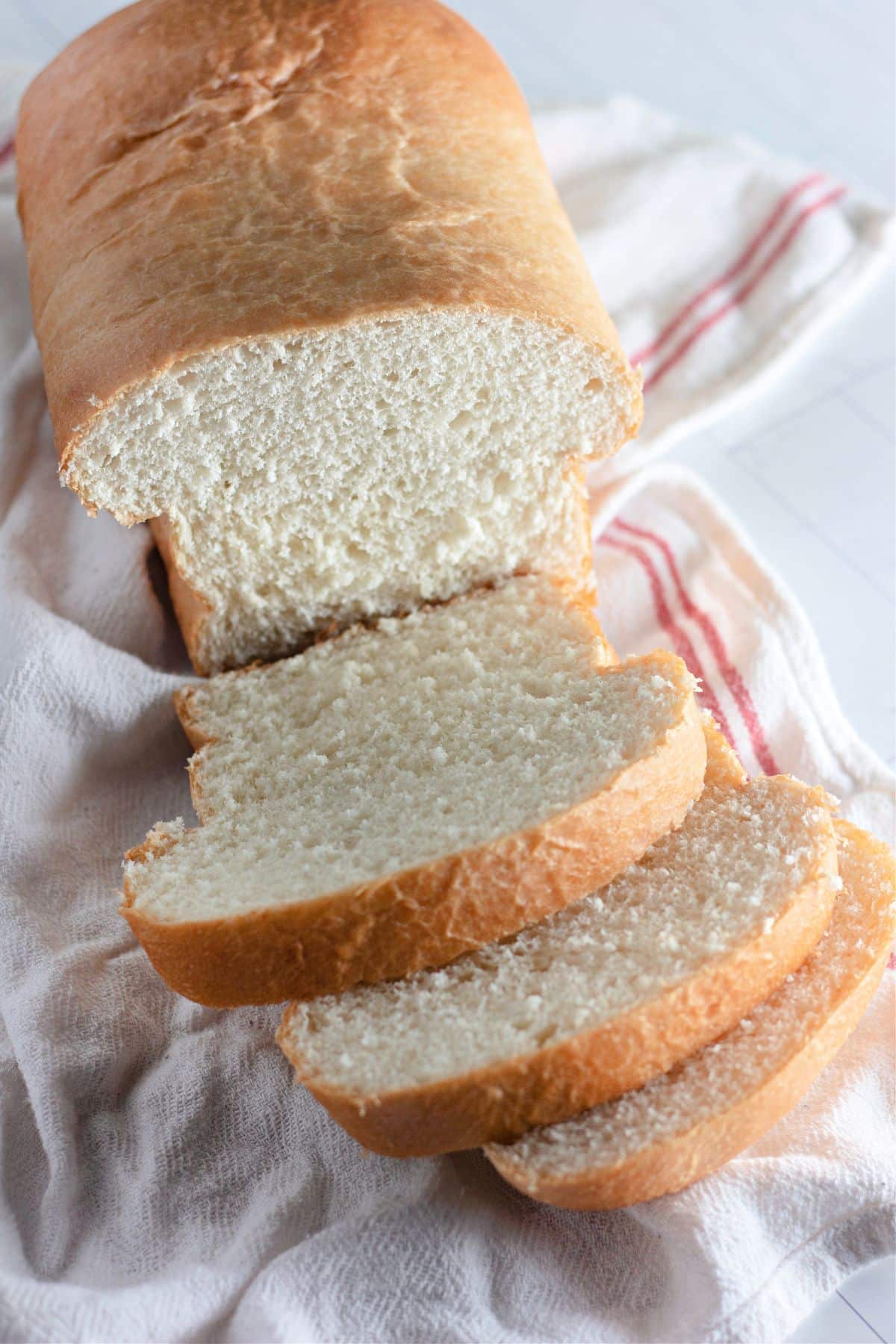 country white bread loaf with three slices cut.