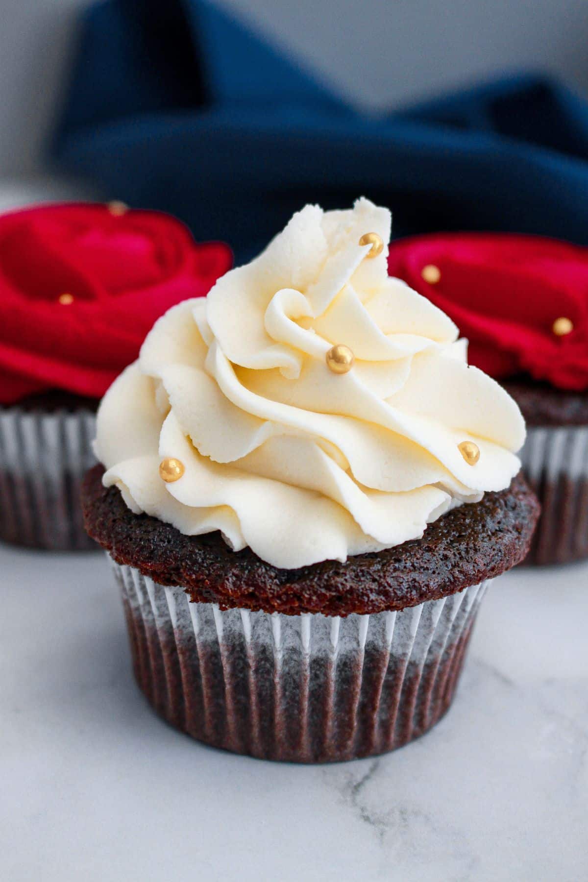 white rosette frosted devils food cupcake on a marble counter.